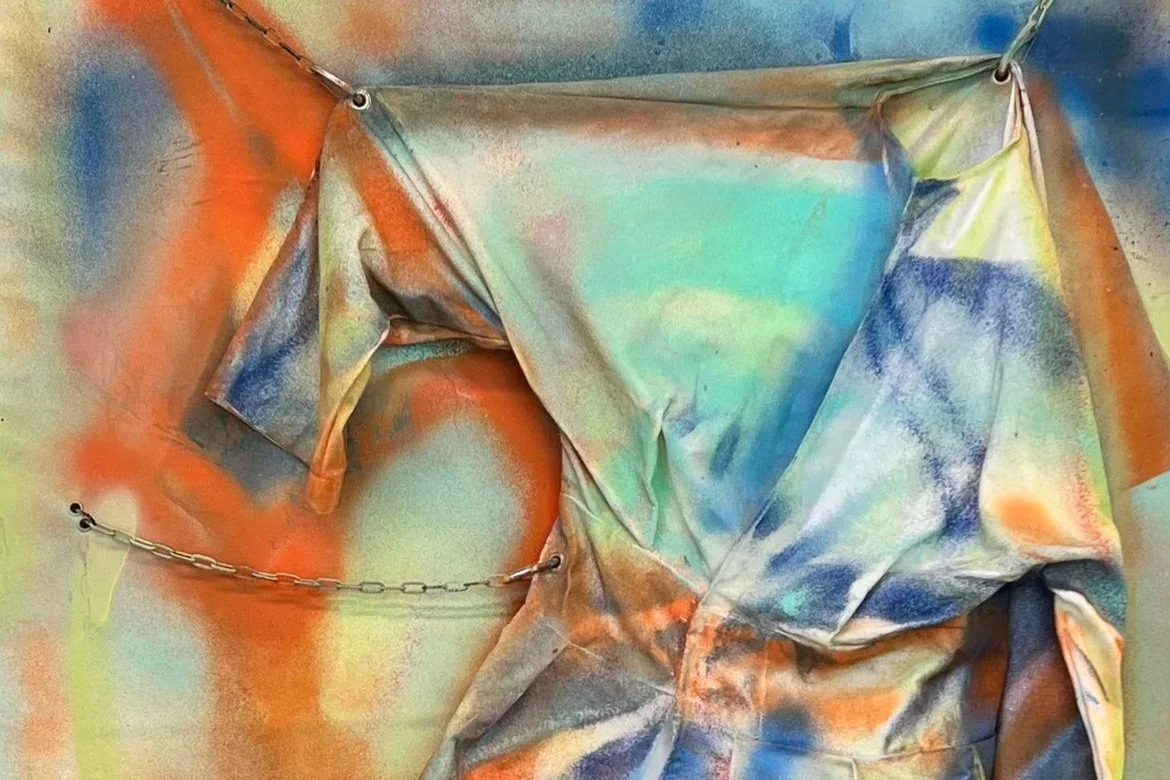 Abstract colorful spray-painted fabric with metal chain attachment.