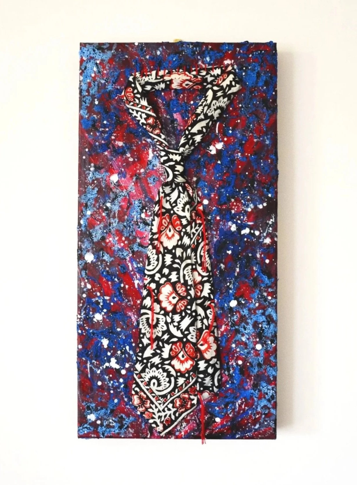 A painting of a bandana tied around a superhero emblem, set against an abstract cosmic background with blue, red, and white splatter patterns.