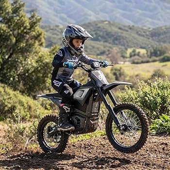 Person riding an electric dirt bike on a trail with green hills and trees in the background.