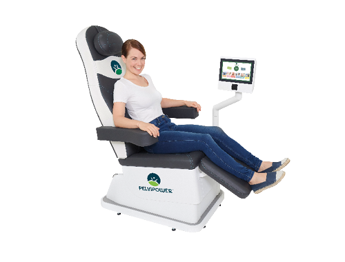 A woman sitting comfortably and smiling in a Pelvipower chair with a computer monitor in front of her, labeled 'Pelvipower'.