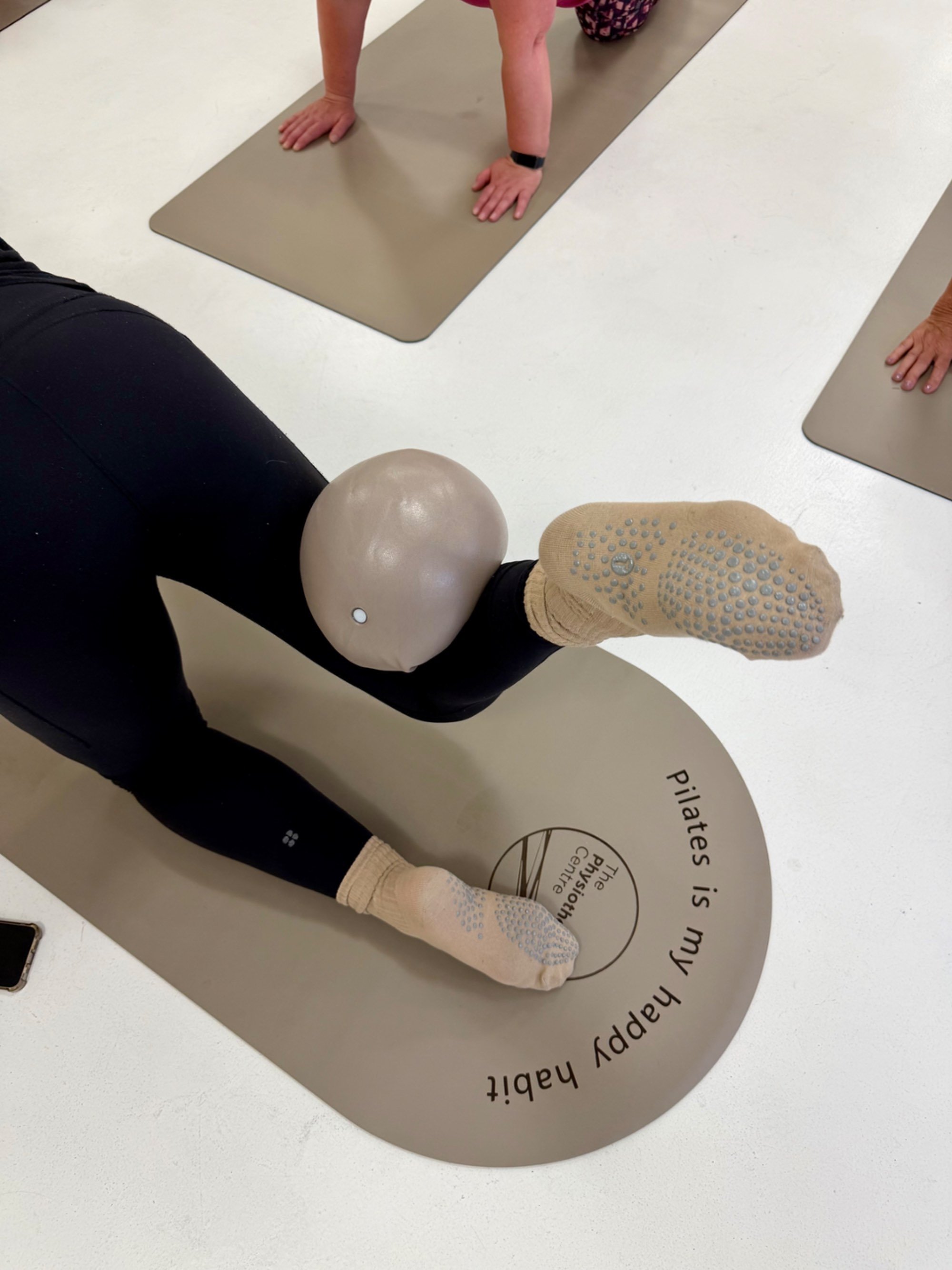A leg balancing a pilates ball in a clinic studio.