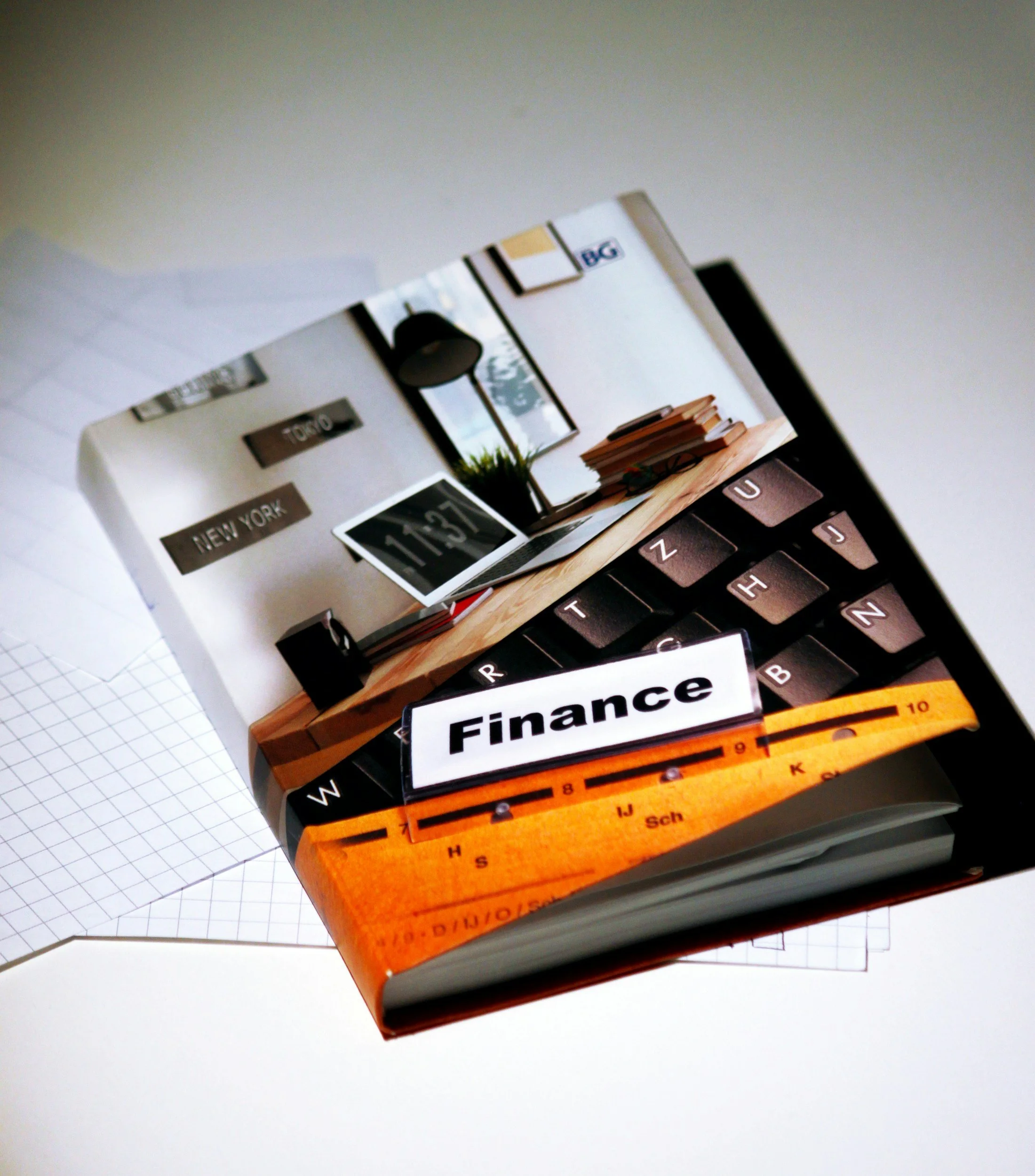 Close-up of a calculator, a ruler, and a small stack of books on a white surface with a grid paper underneath.