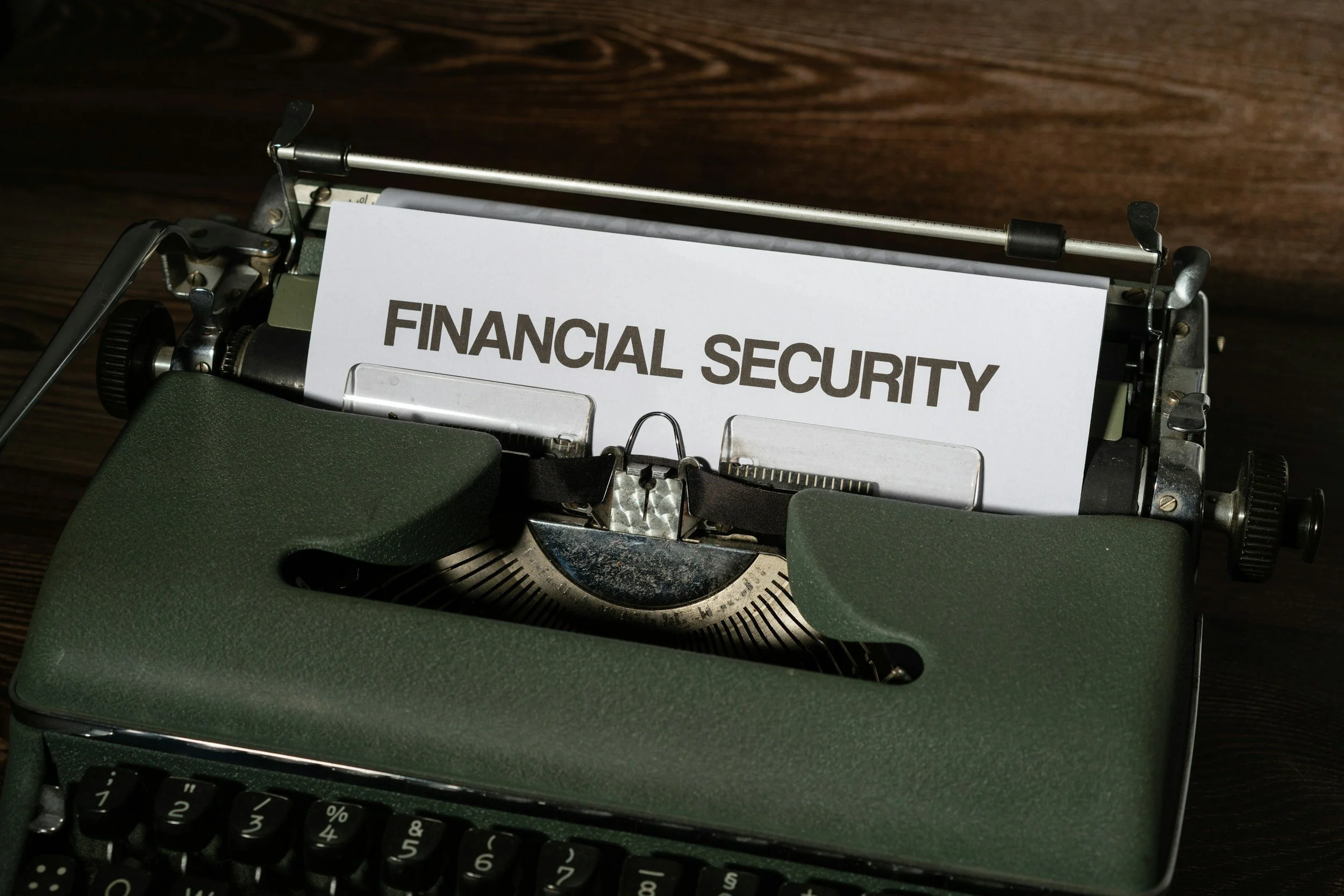 A vintage typewriter with a sheet of paper that reads "FINANCIAL SECURITY" on a wooden surface.