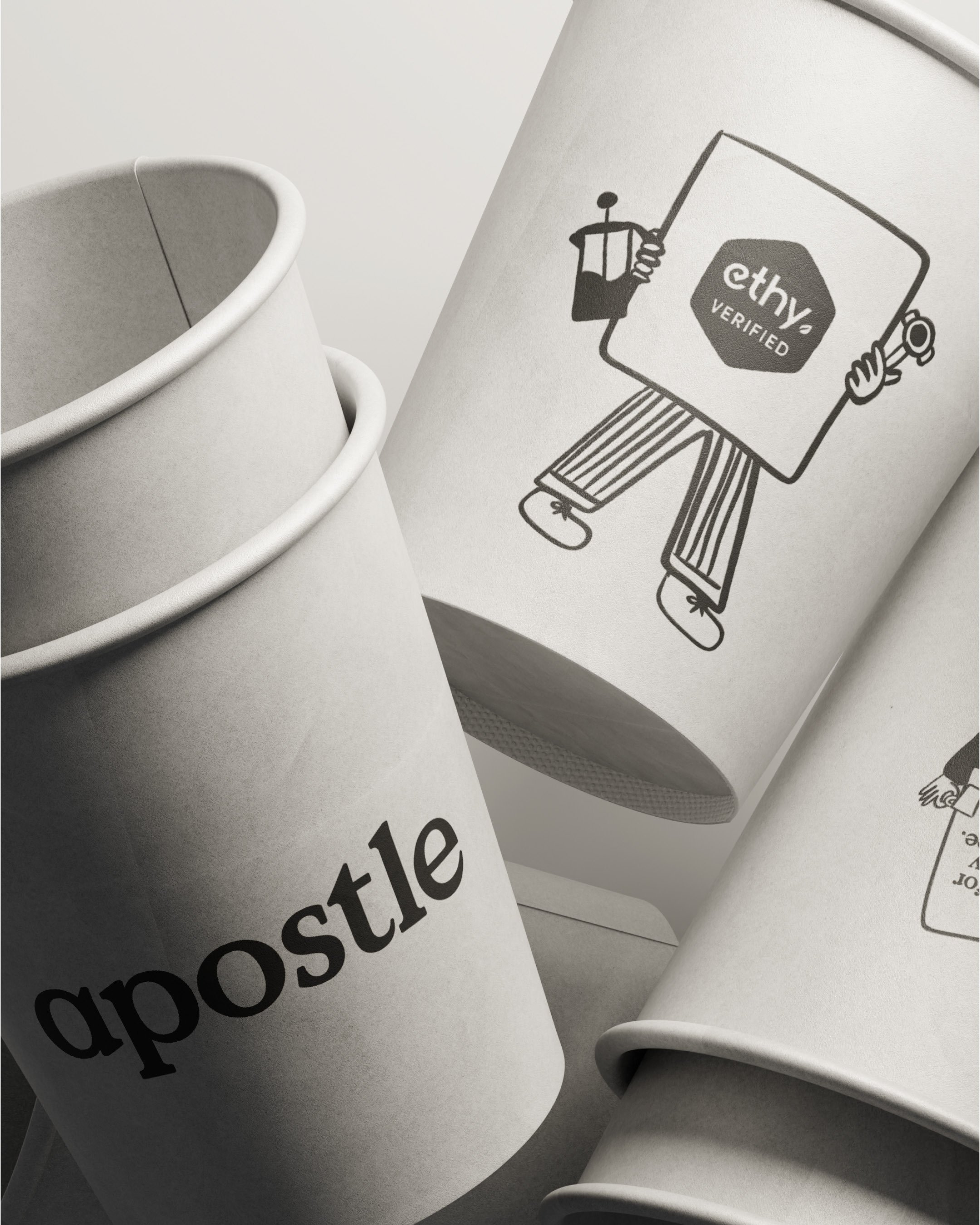 Close-up of white paper cups and a piece of paper with a black and white drawing of a person holding a tool and a sign that says 'ethy verified.' The cups are stacked and have a textured surface.