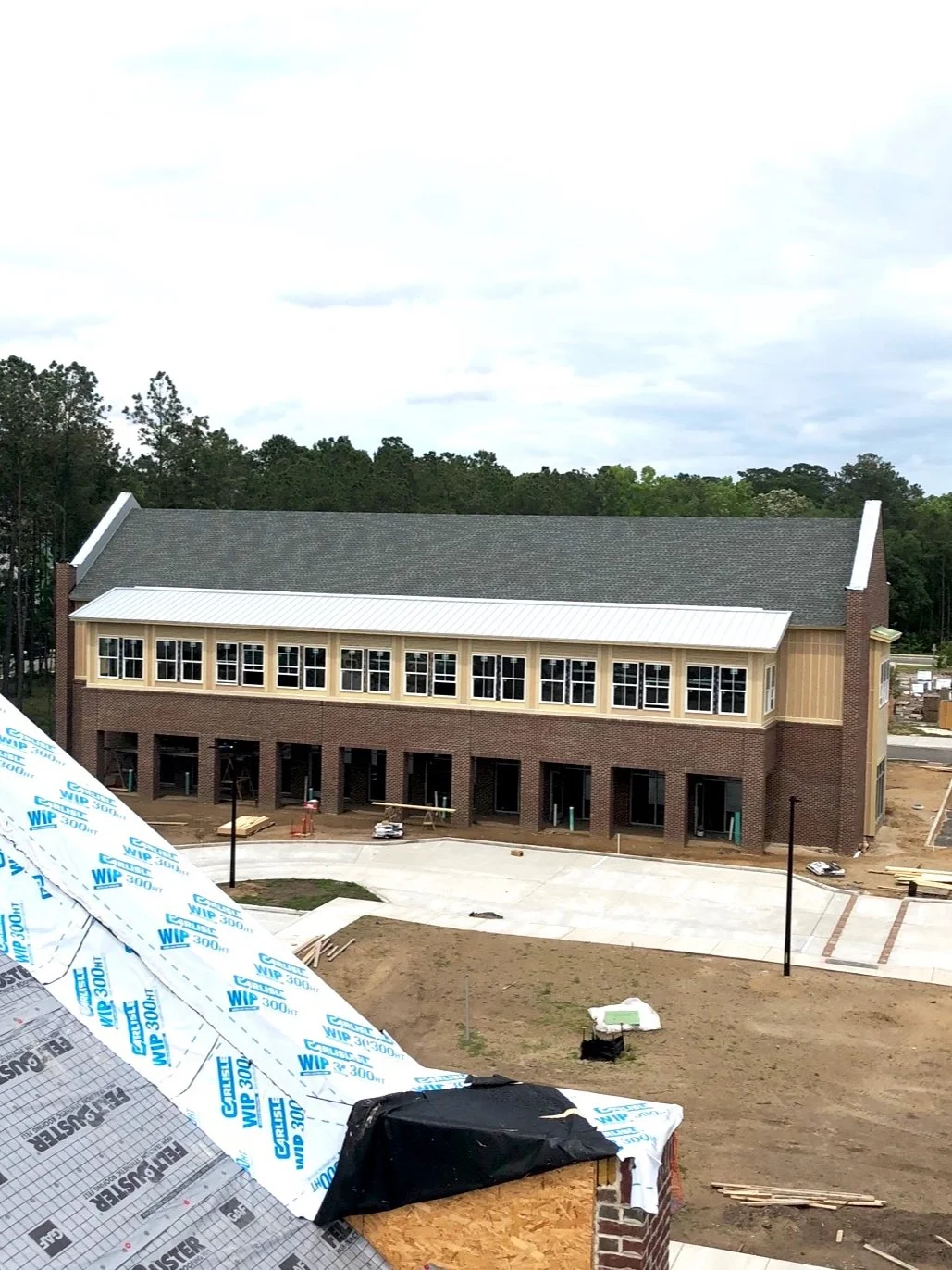 Under construction multi-story brick building, with some windows installed and scaffolding around the structure.