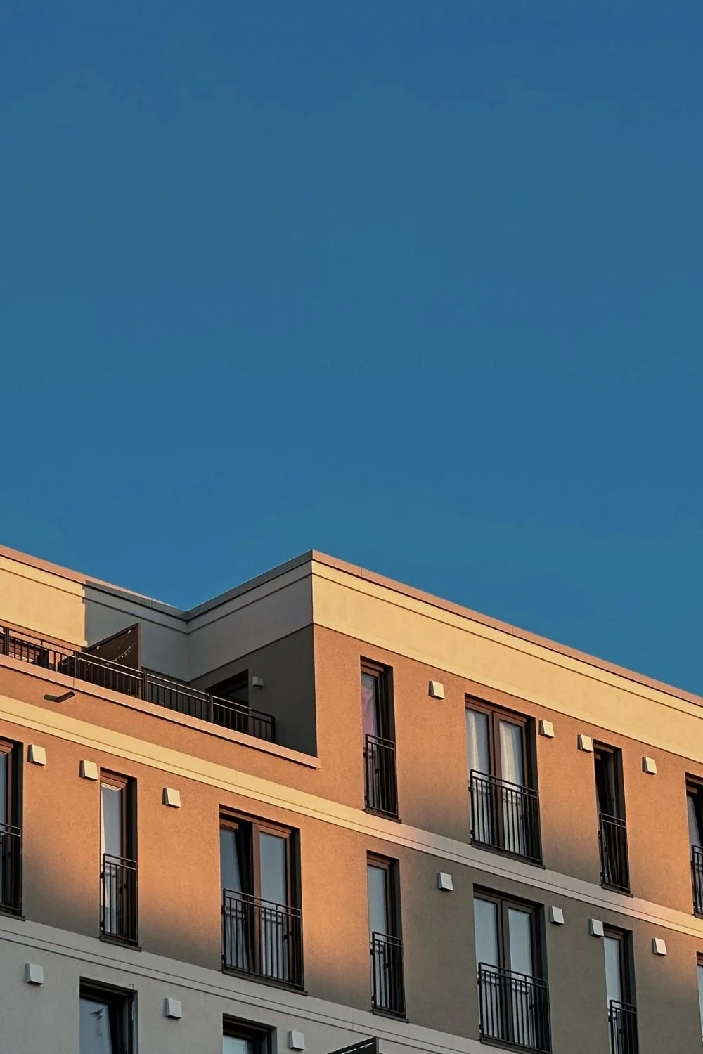 Modern multifamily residential building with balconies and clean architectural design, showcasing the type of investment properties developed and managed by Ivy Park Properties.