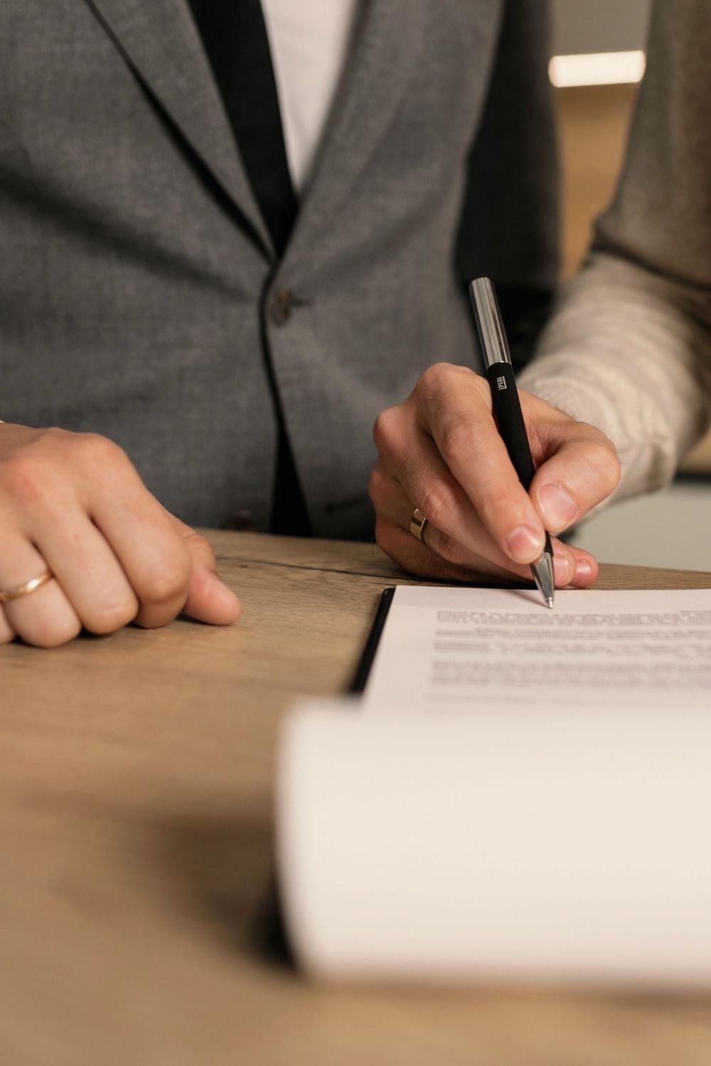 Real estate professional signing transaction documents at a conference table, representing the acquisition and management of commercial real estate properties and net lease investment properties for long-term portfolio growth.