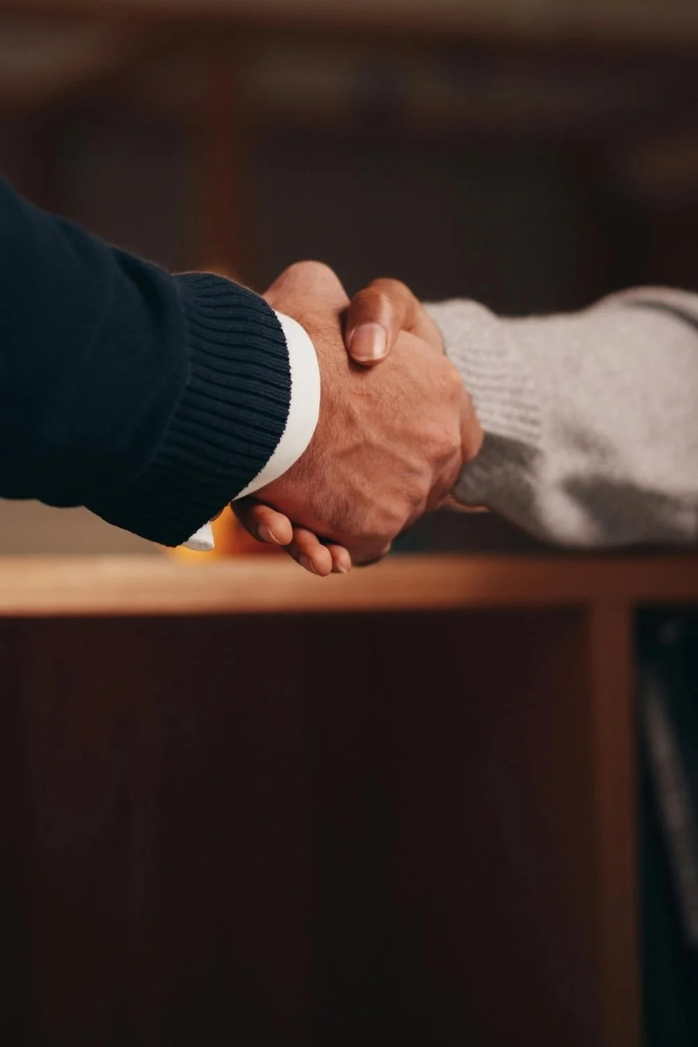 Two professionals shaking hands during a business meeting, symbolizing investor partnerships, nnn real estate investments, and commercial property acquisition opportunities.