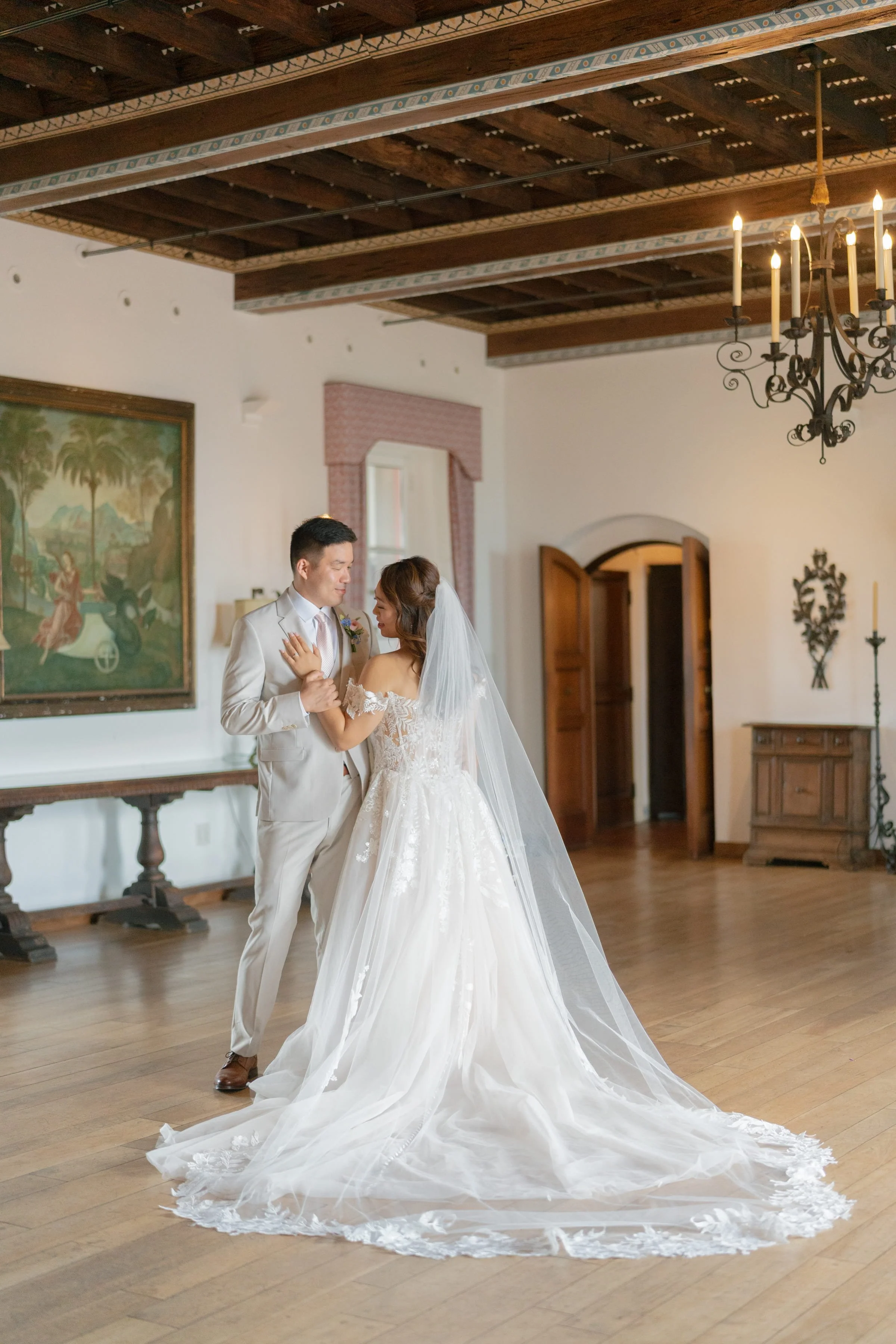 A bride and groom dancing in a rustic room with wooden beams and vintage decor.