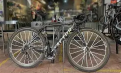 A black bicycle with thin tires and a sleek frame parked indoors, possibly in a bike shop or store.