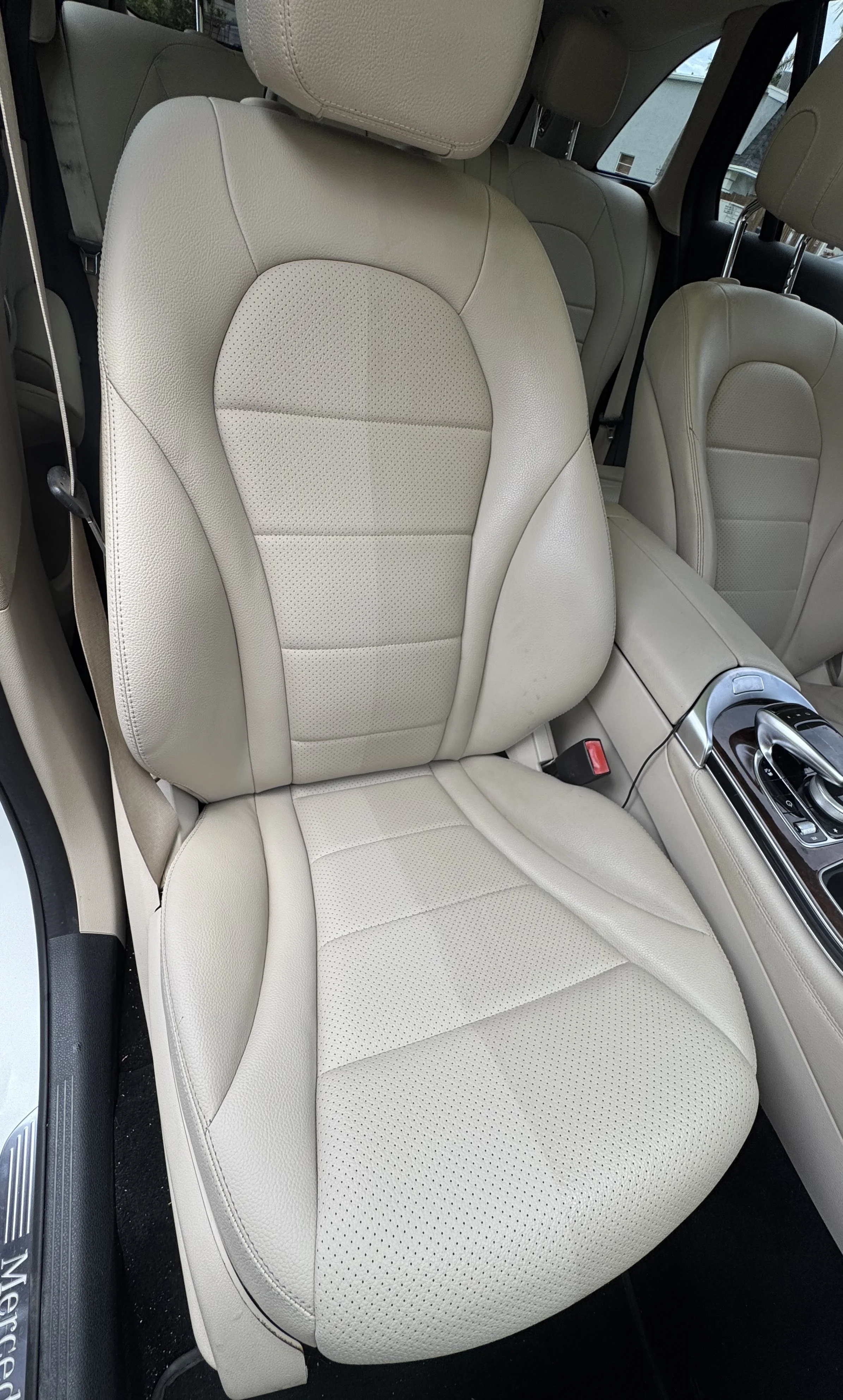 Interior of a car showing beige leather seats, front passenger seat, and part of the center console.