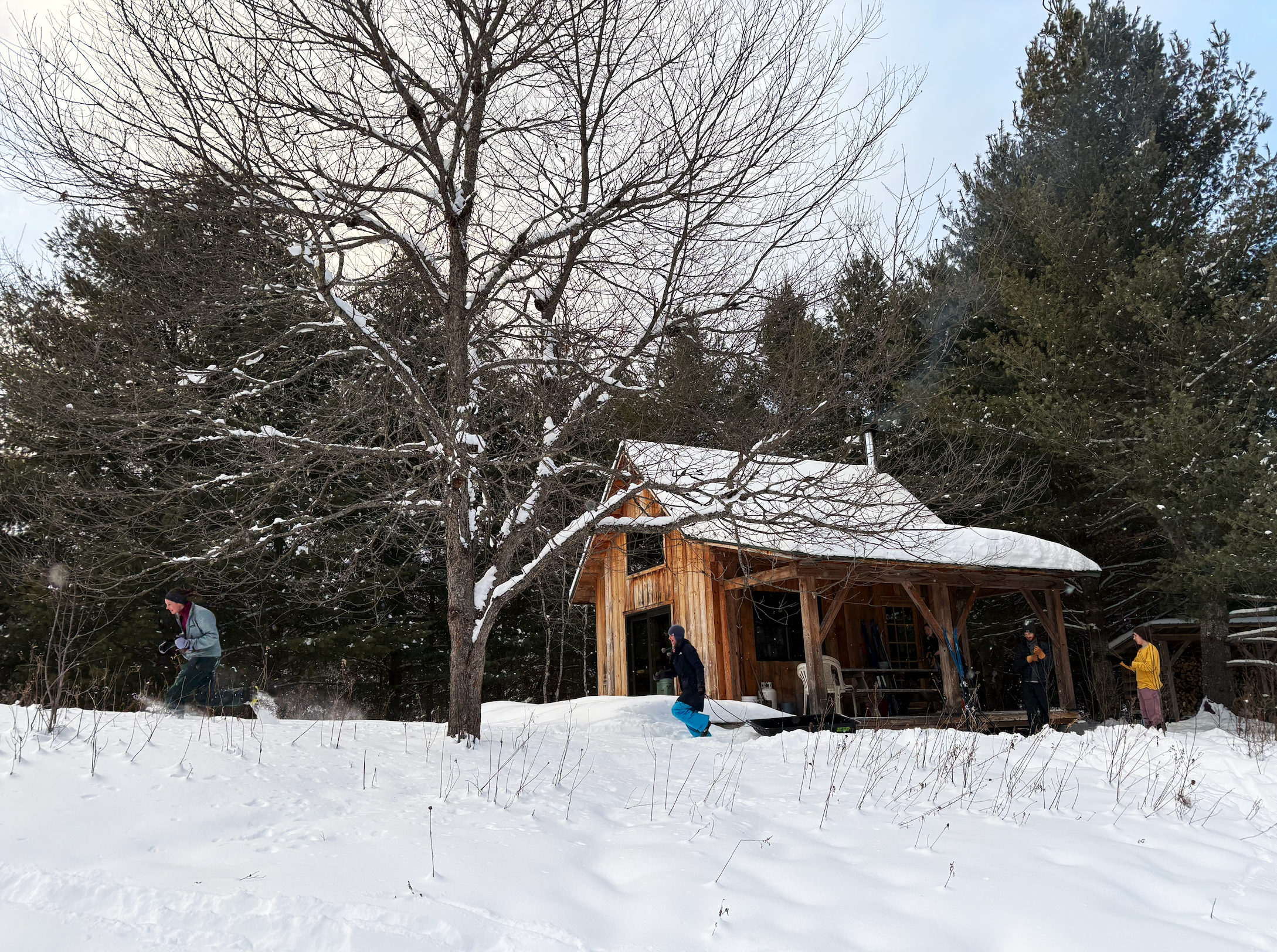 Students running through the snow in front of a cabin in the woods