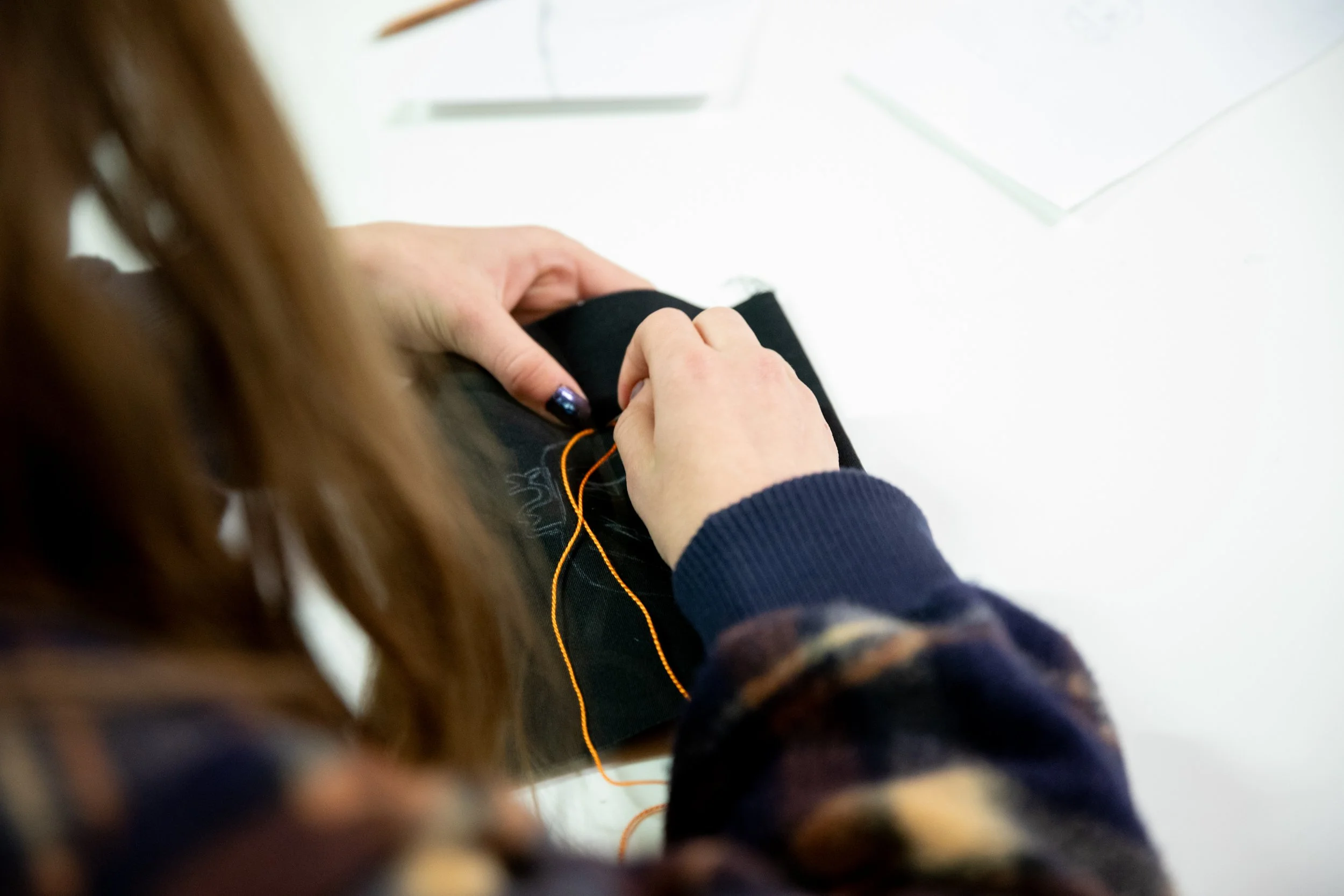 Hands of a student sewing in Handwork class