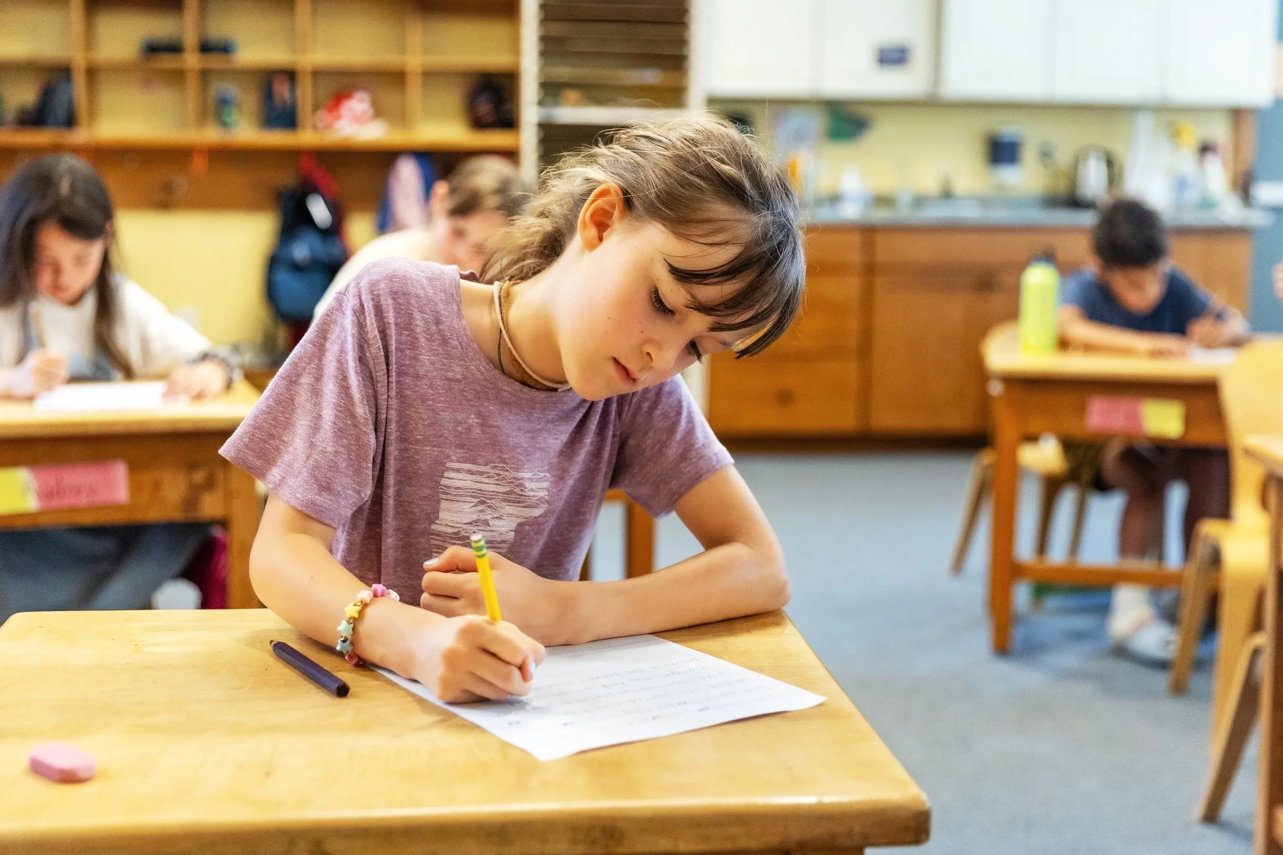 Girl writing at her desk in a classroom