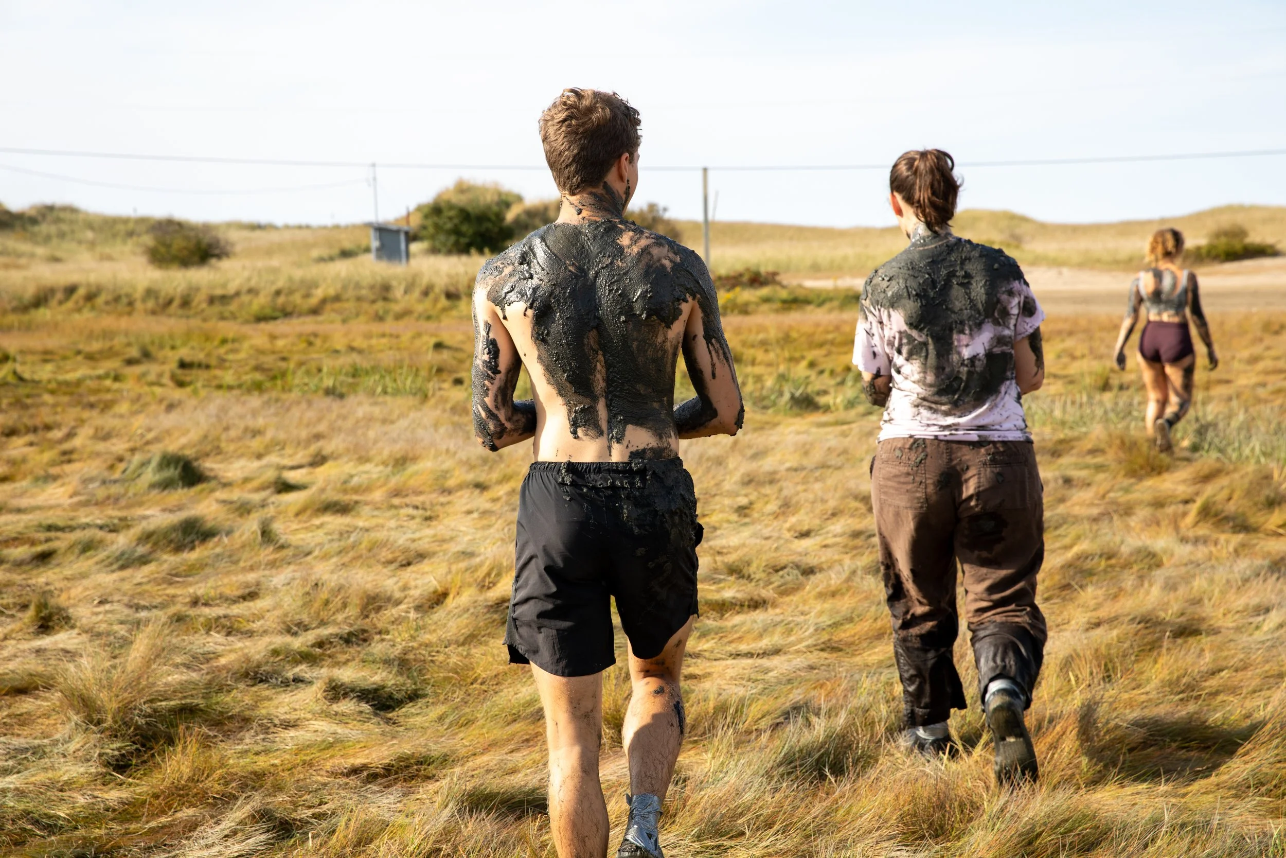 High school student covered in mud walking through a field