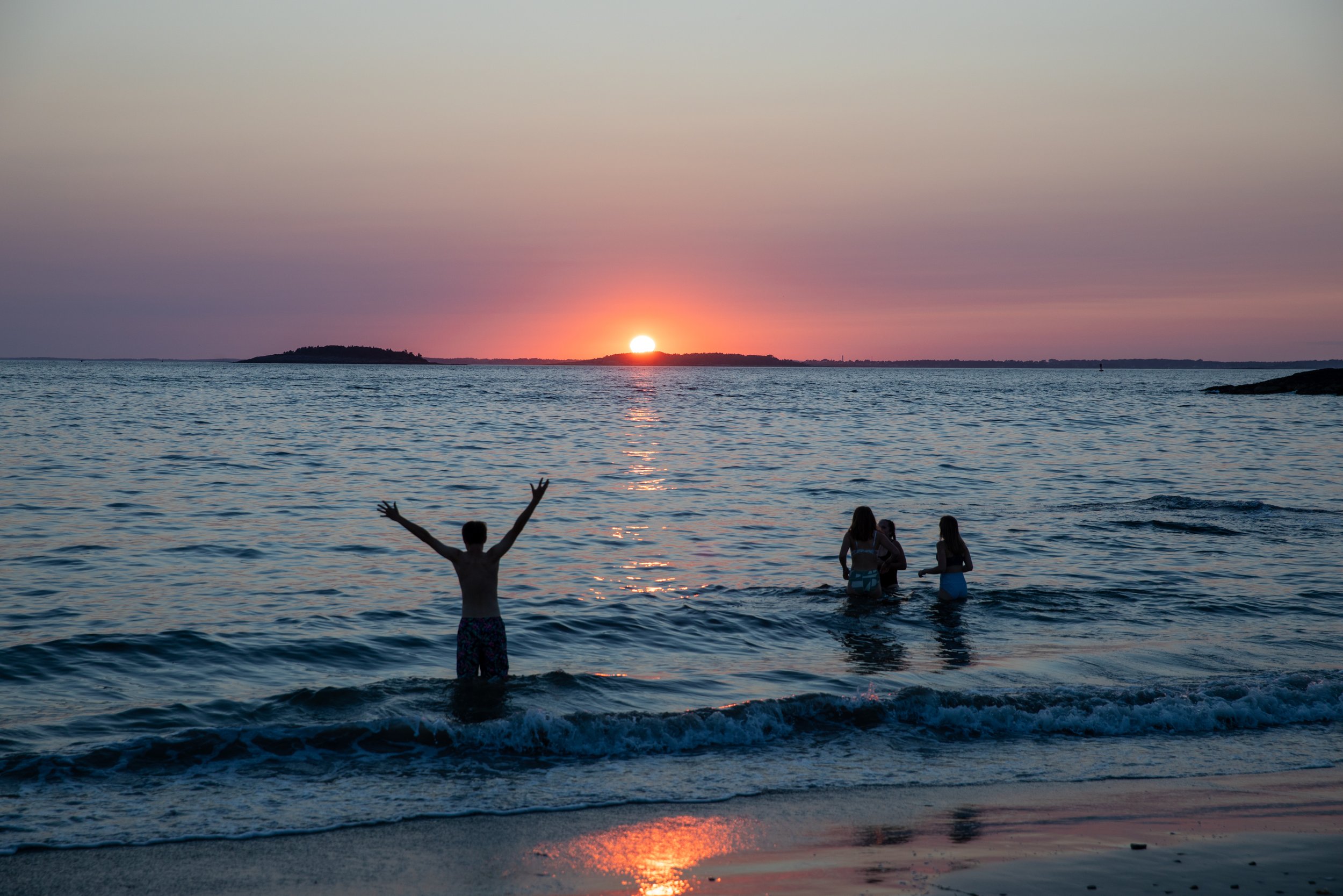 Students in the ocean watching the sunset