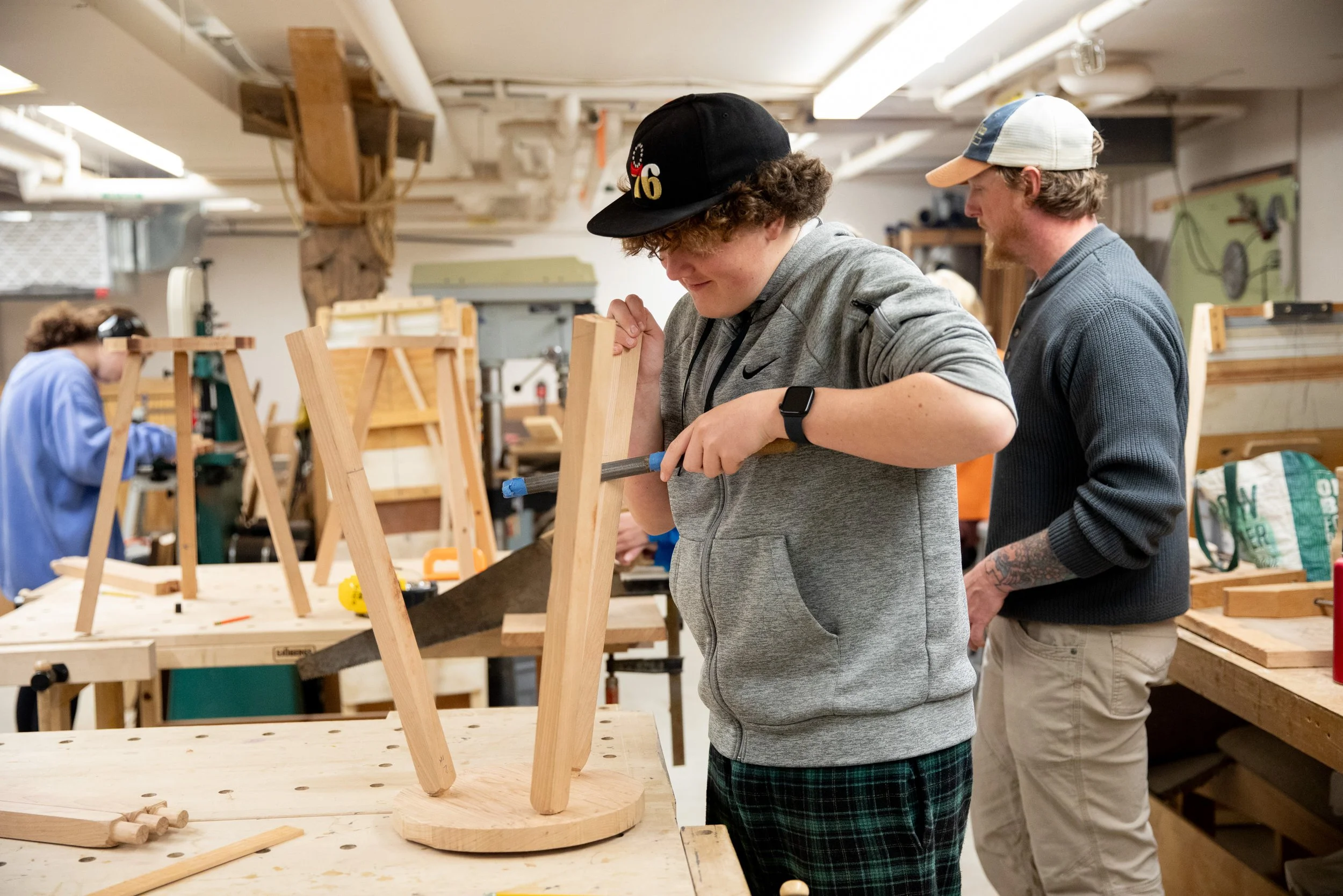 Boy carving a stool in woodworking class