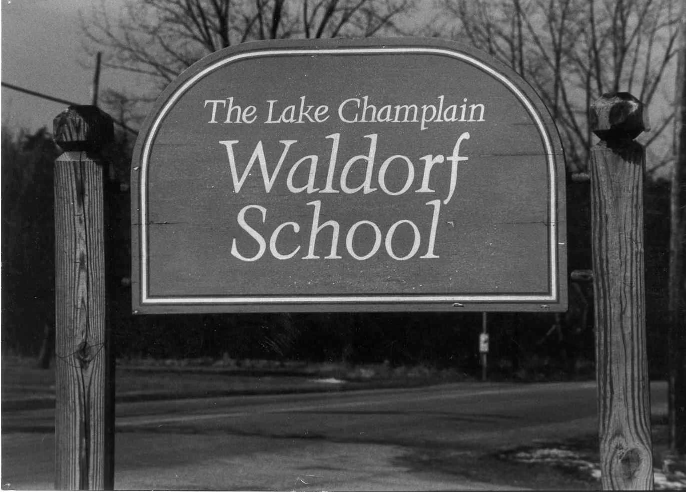 Black and white sign for the Lake Champlain Waldorf School, mounted on two wooden posts.