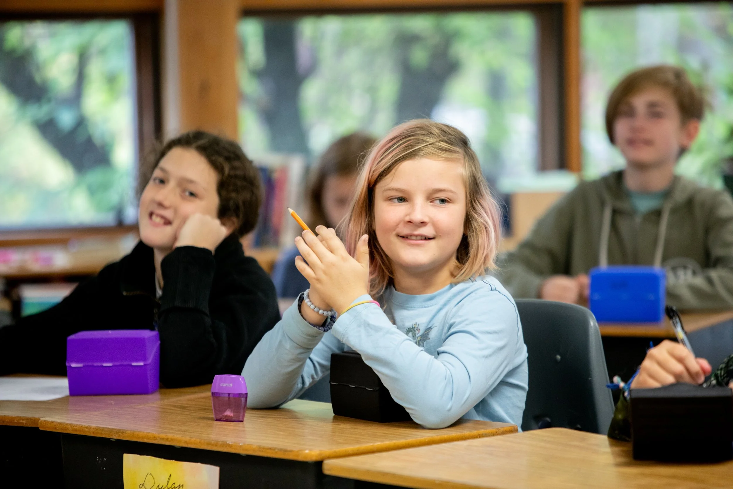 Students smiling at their desks in a classroom