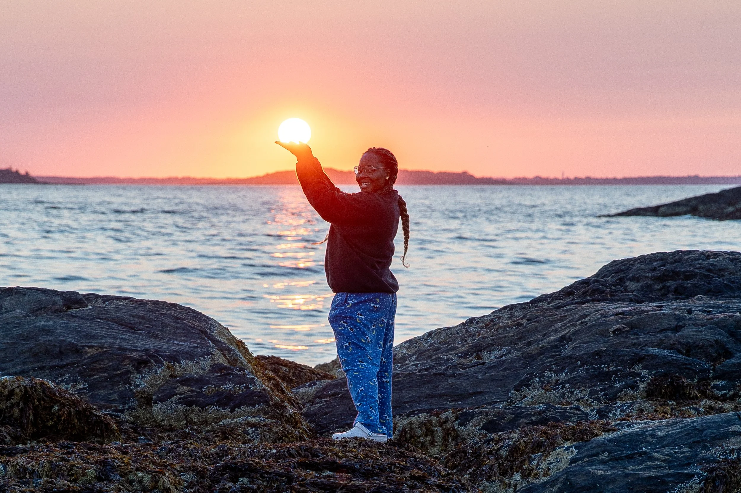 Girl posing on the beach holding the sun in her hands