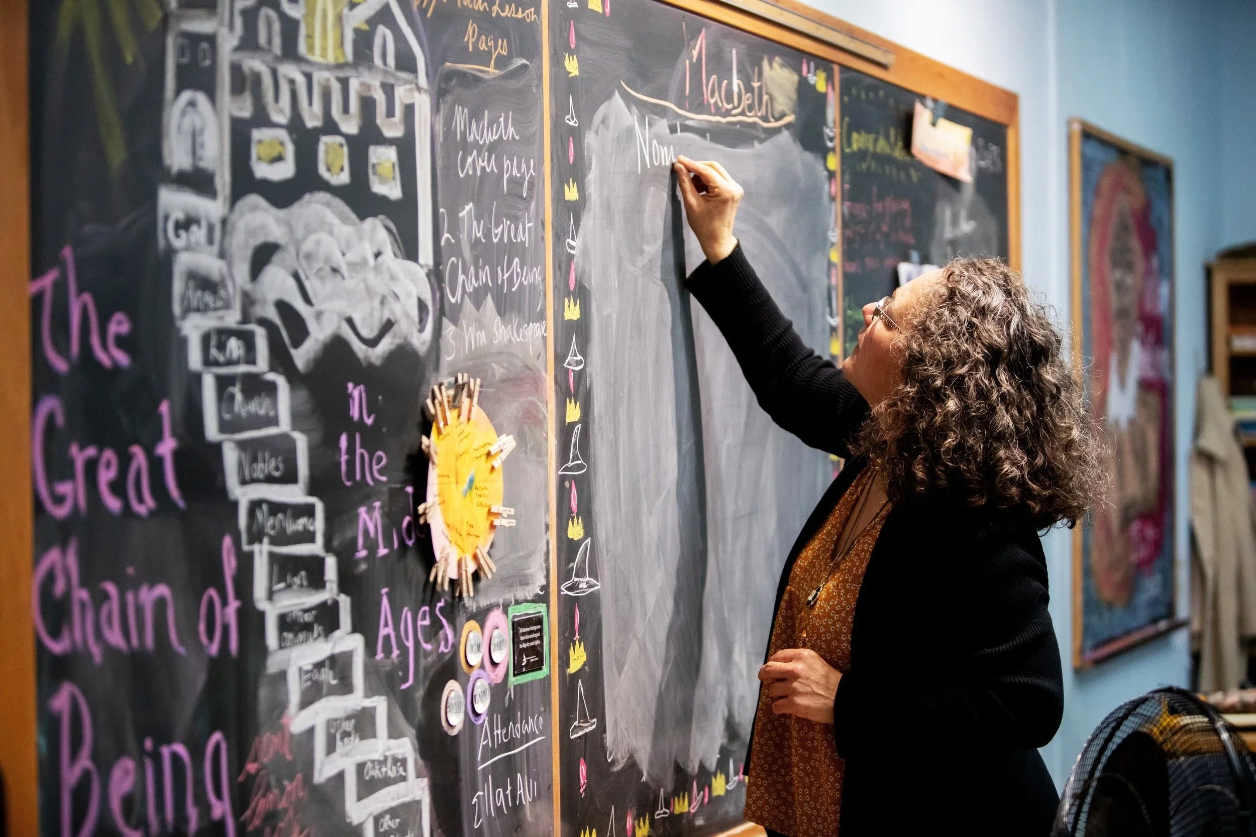 Teacher writing on a colorful chalkboard
