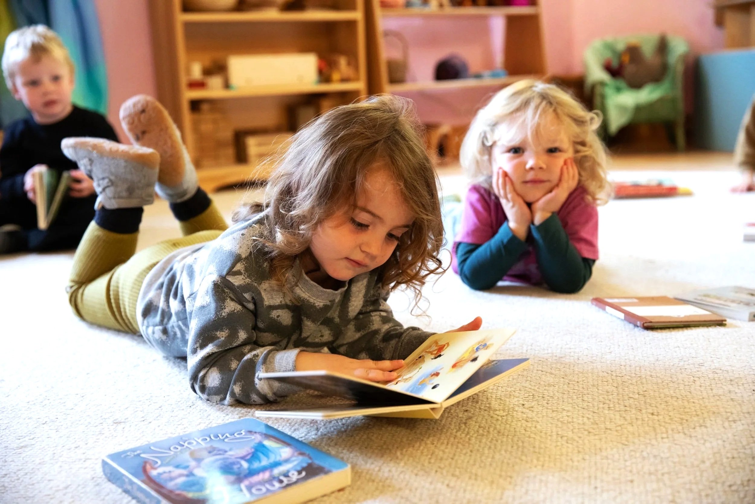 Young children laying on a carpet in their classroom reading