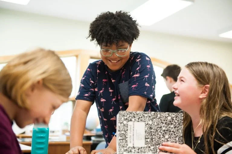 Three students laughing while working together