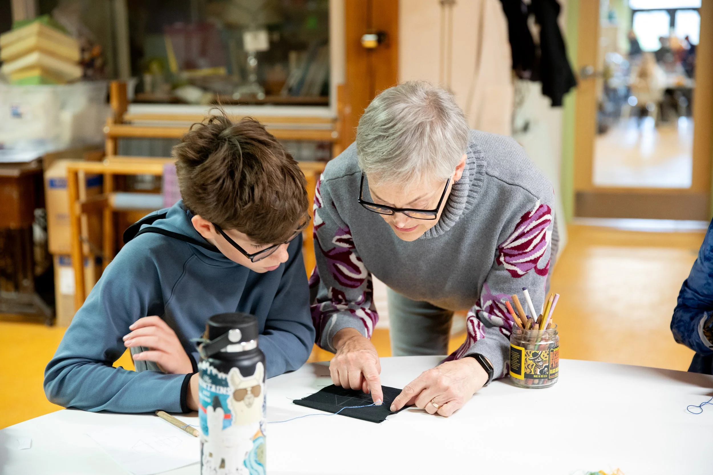 Teacher showing a student how to improve his sewing