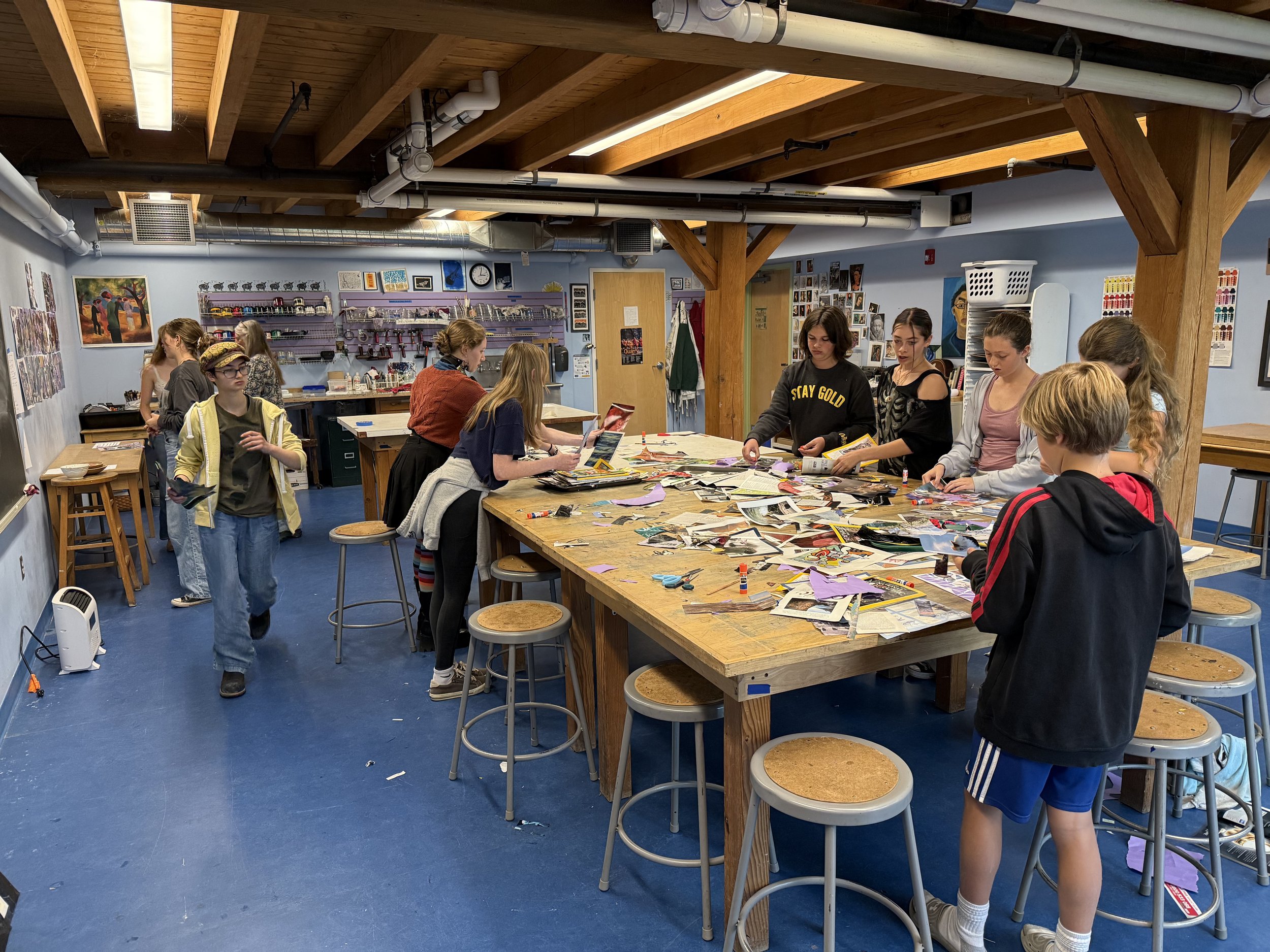 Students standing around a table with fabric scraps and magazines