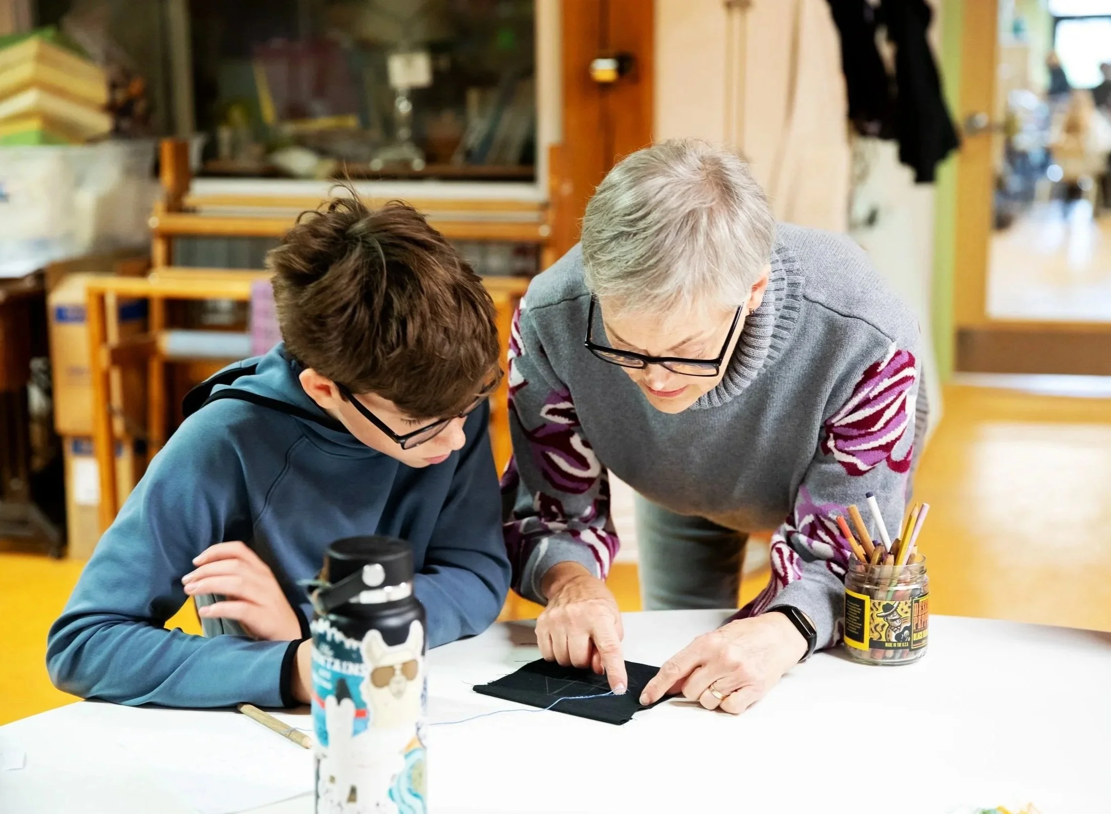 Teacher showing a boy how to improve his sewing