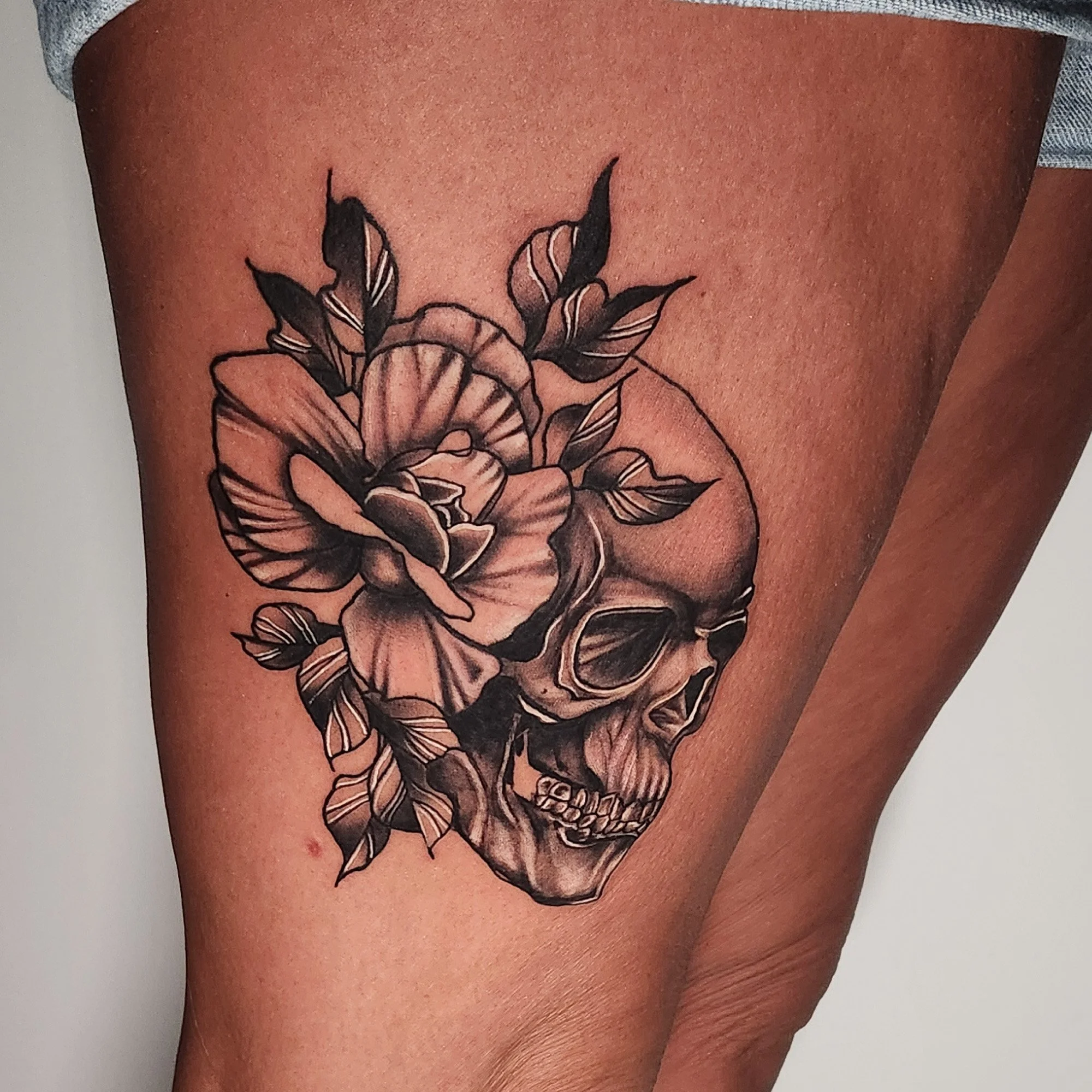 Black and grey skull with flower tattoo