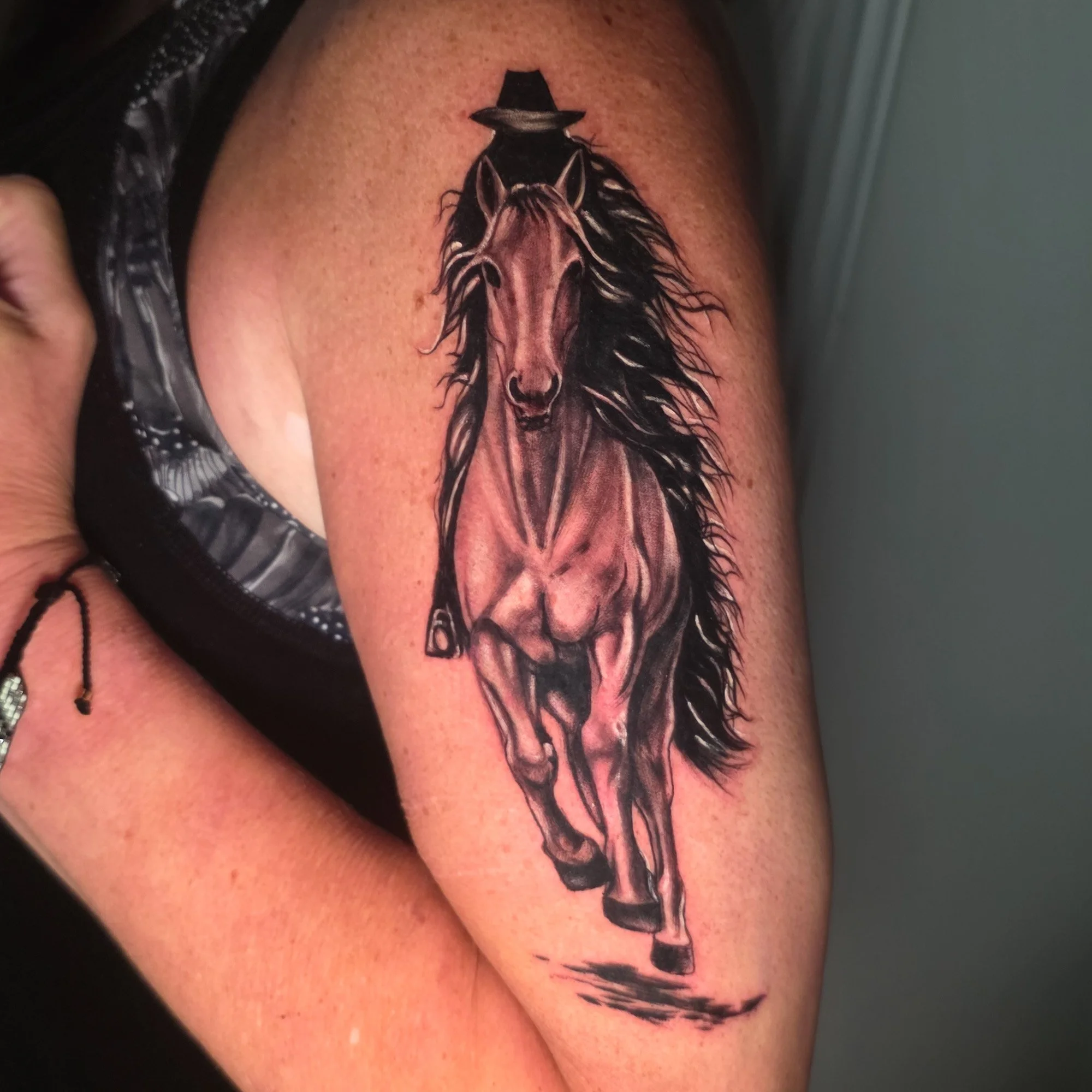 Tattoo of a wolf wearing a hat on upper arm.