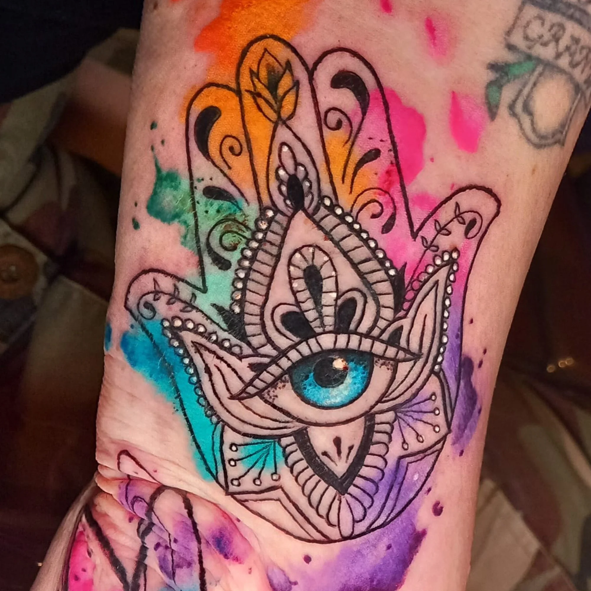 Colorful tattoo of a mystical hand with an eye