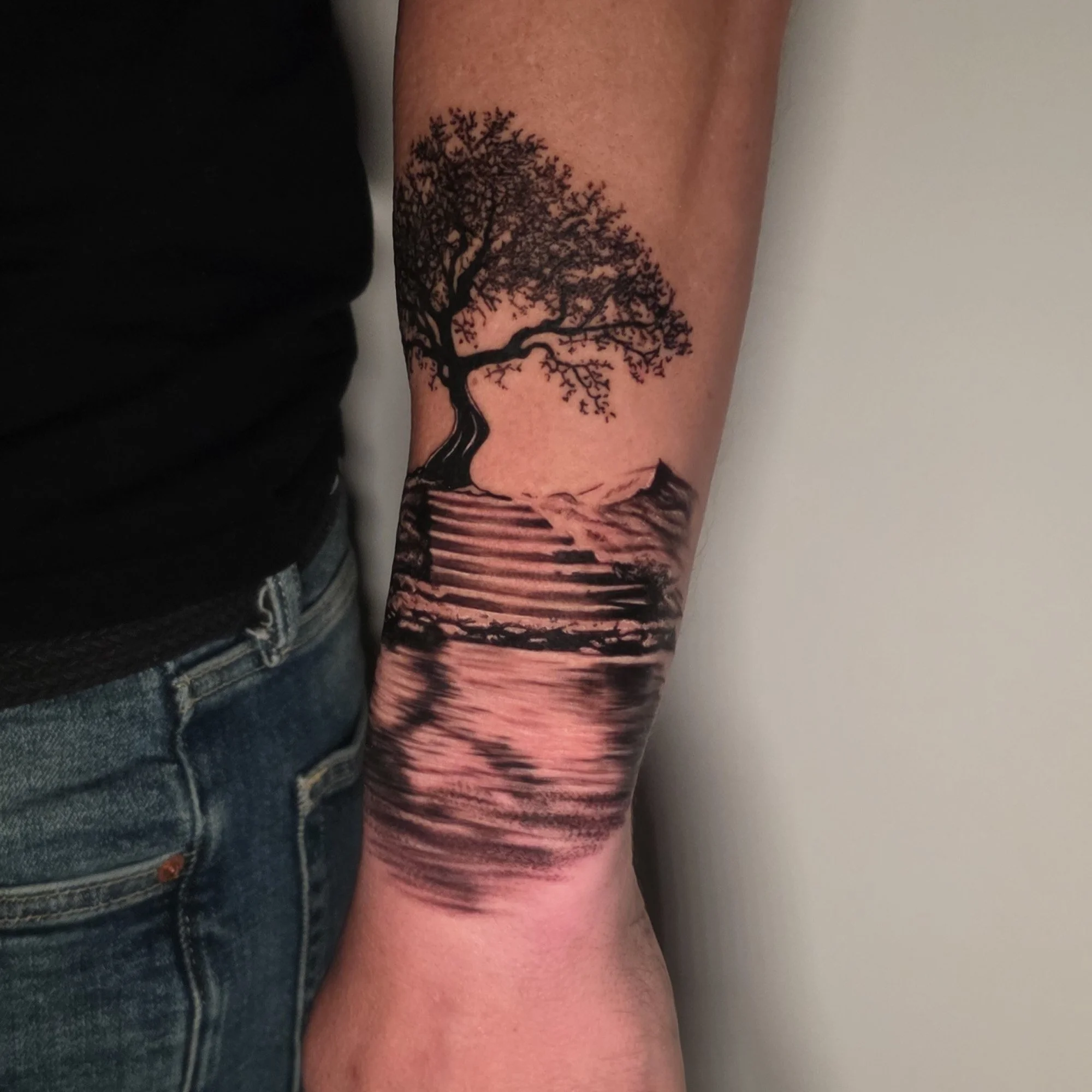 Tattoo of a large, detailed tree with many branches on a person's forearm.