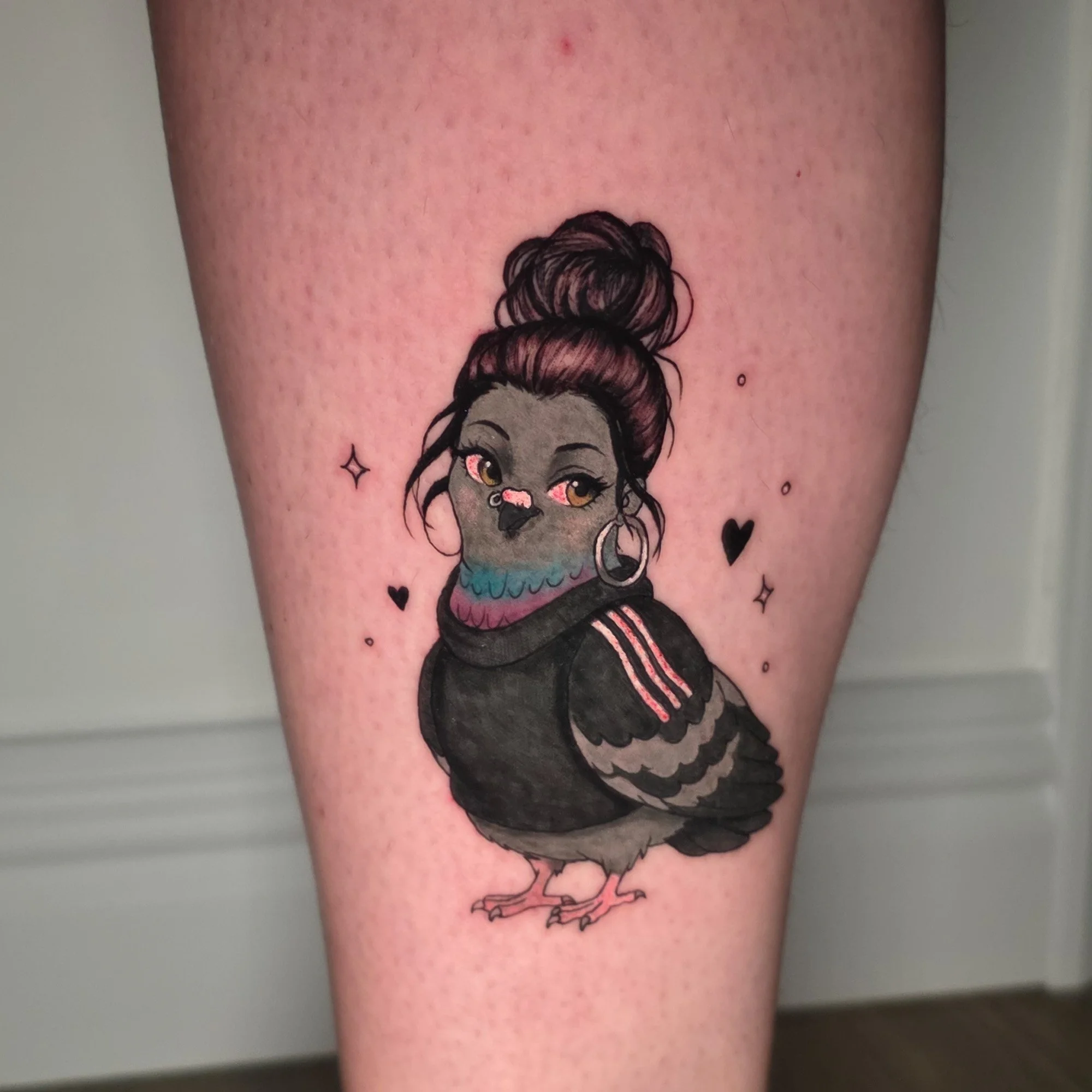 Tattoo of a girl with a bun hairstyle, large earrings, and makeup, surrounded by small decorative stars, on a person's arm.
