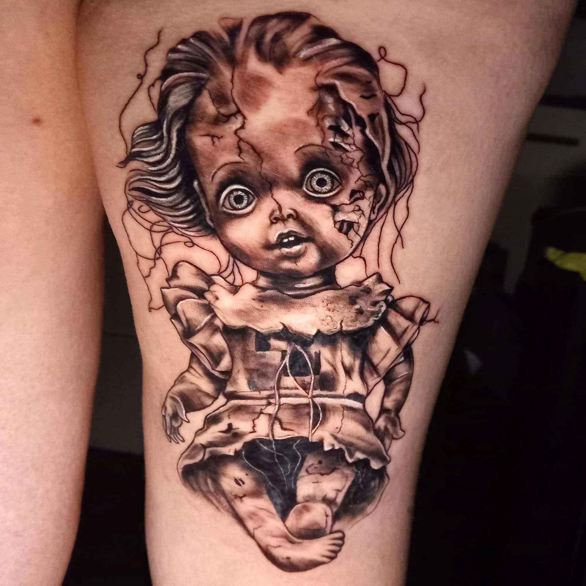 Tattoo of an upside-down child with big eyes and curly hair on person's skin.