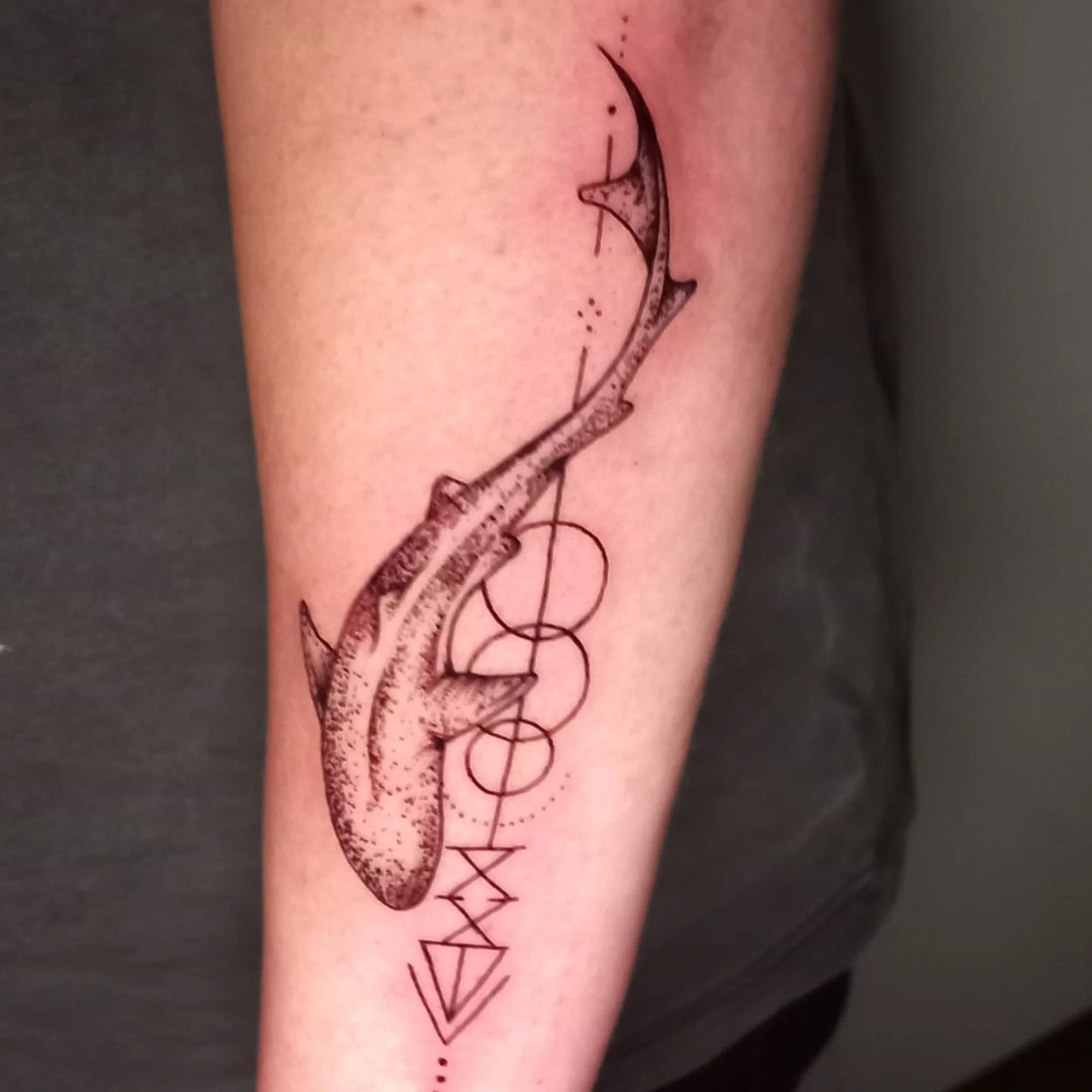 Tattoo of a schematic electric guitar outline with decorative elements on a person's upper arm.