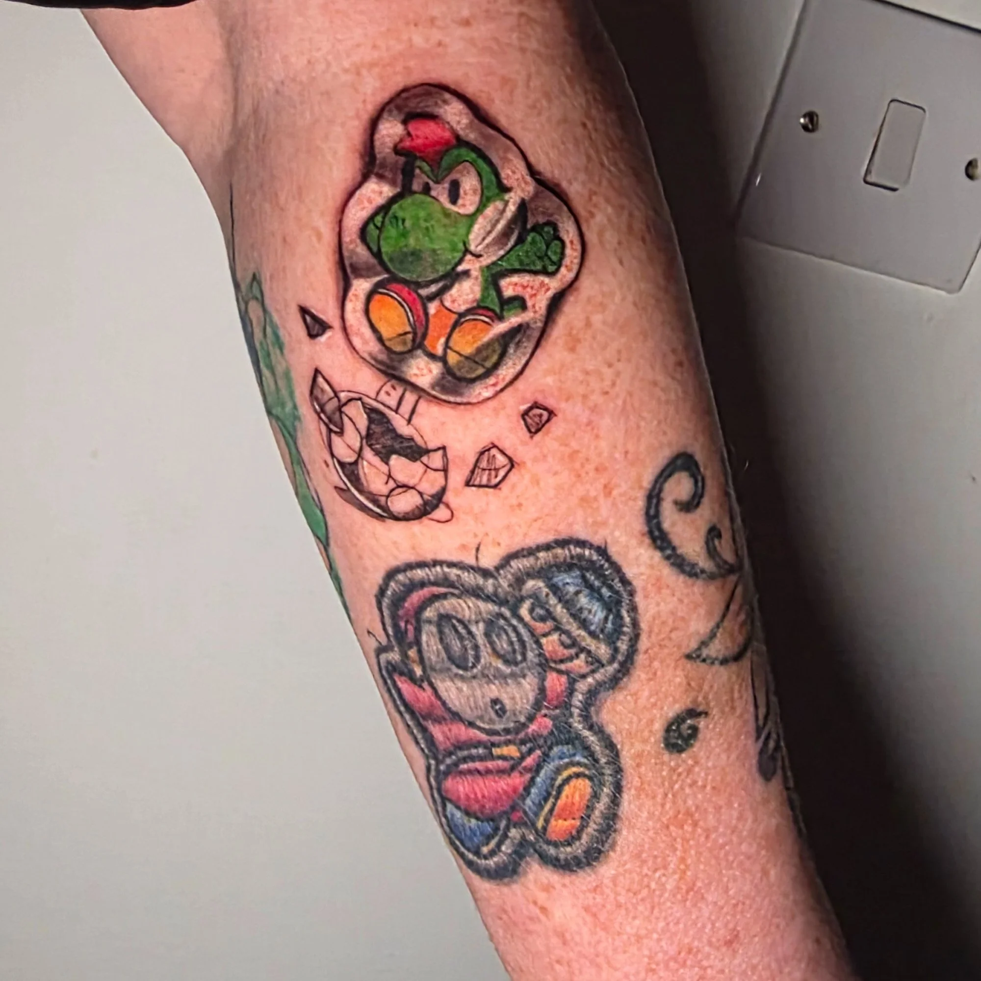 Close-up of a person's upper arm tattoo featuring a cartoon yoshi character.