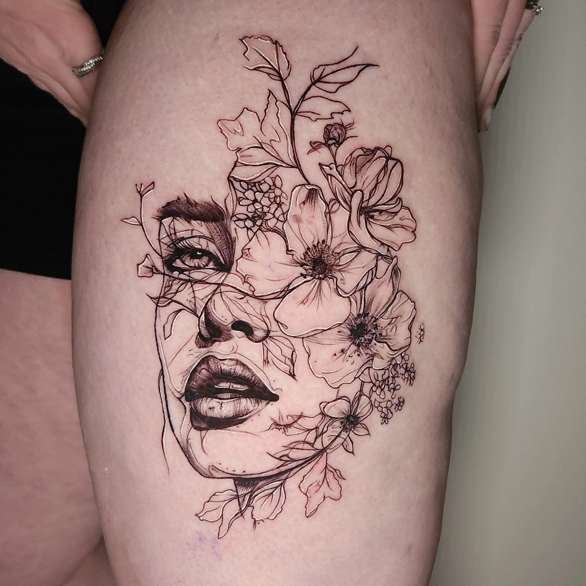 Tattoo of a sketchy woman's face with sketchy flowers
