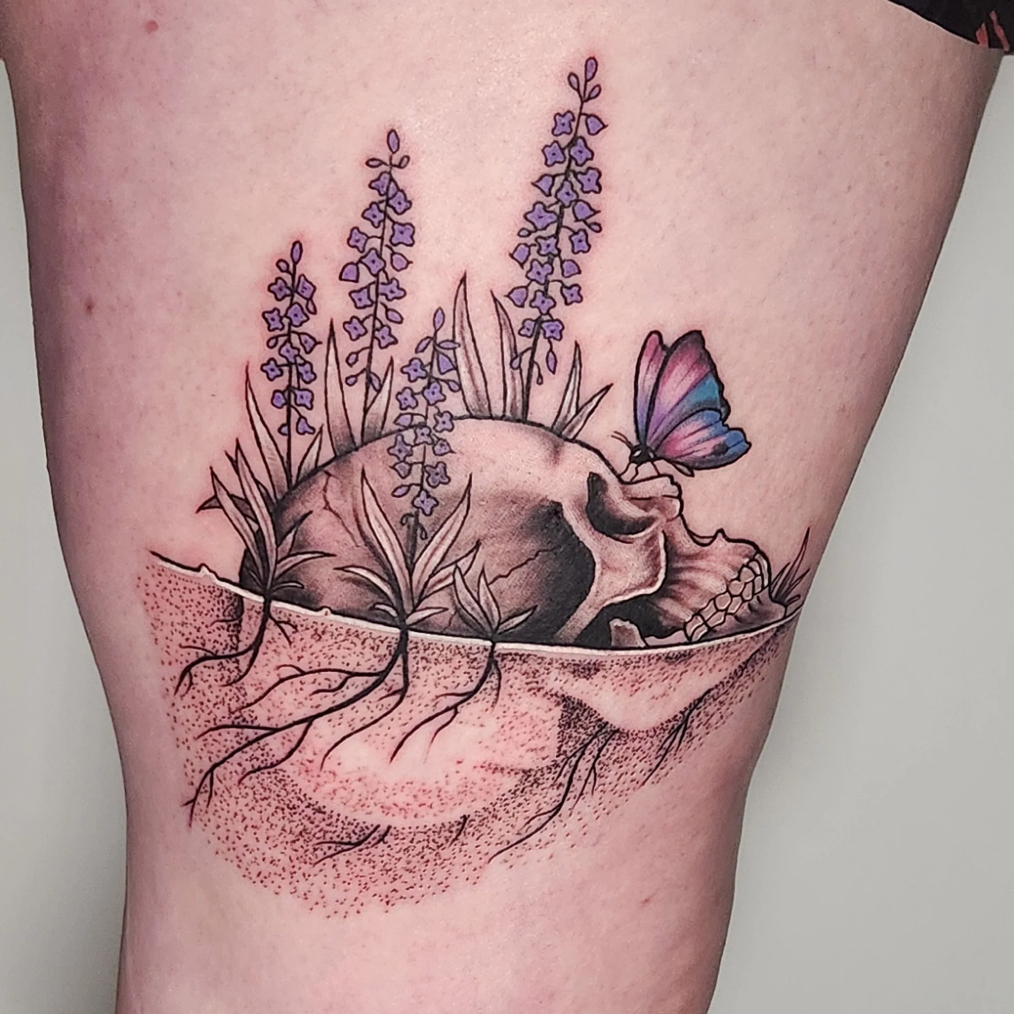 Black and grey skull with splashes of colour on butterfly and flowers