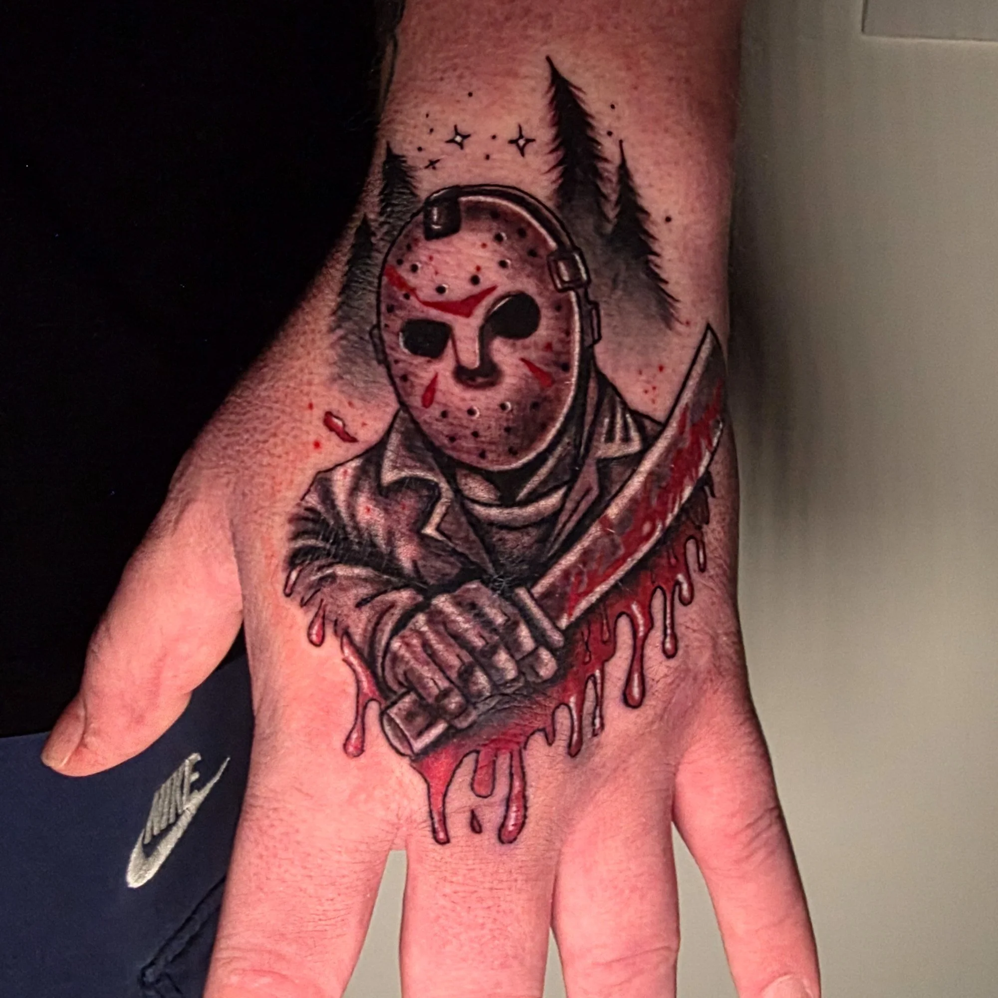 Tattoo of a skull wearing a gas mask with trees and stars in the background on a person's arm.