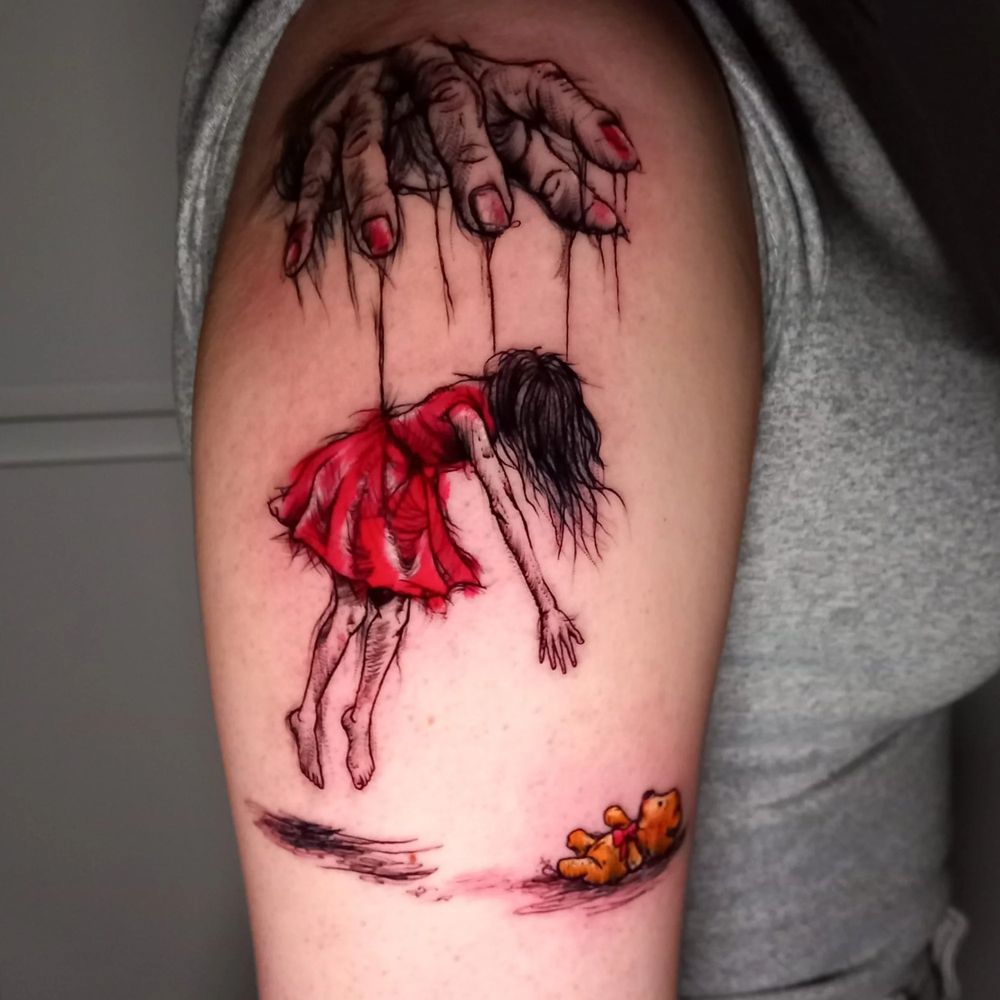 Tattoo of a girl in a red dress with dark hair being held up by a creepy hand.