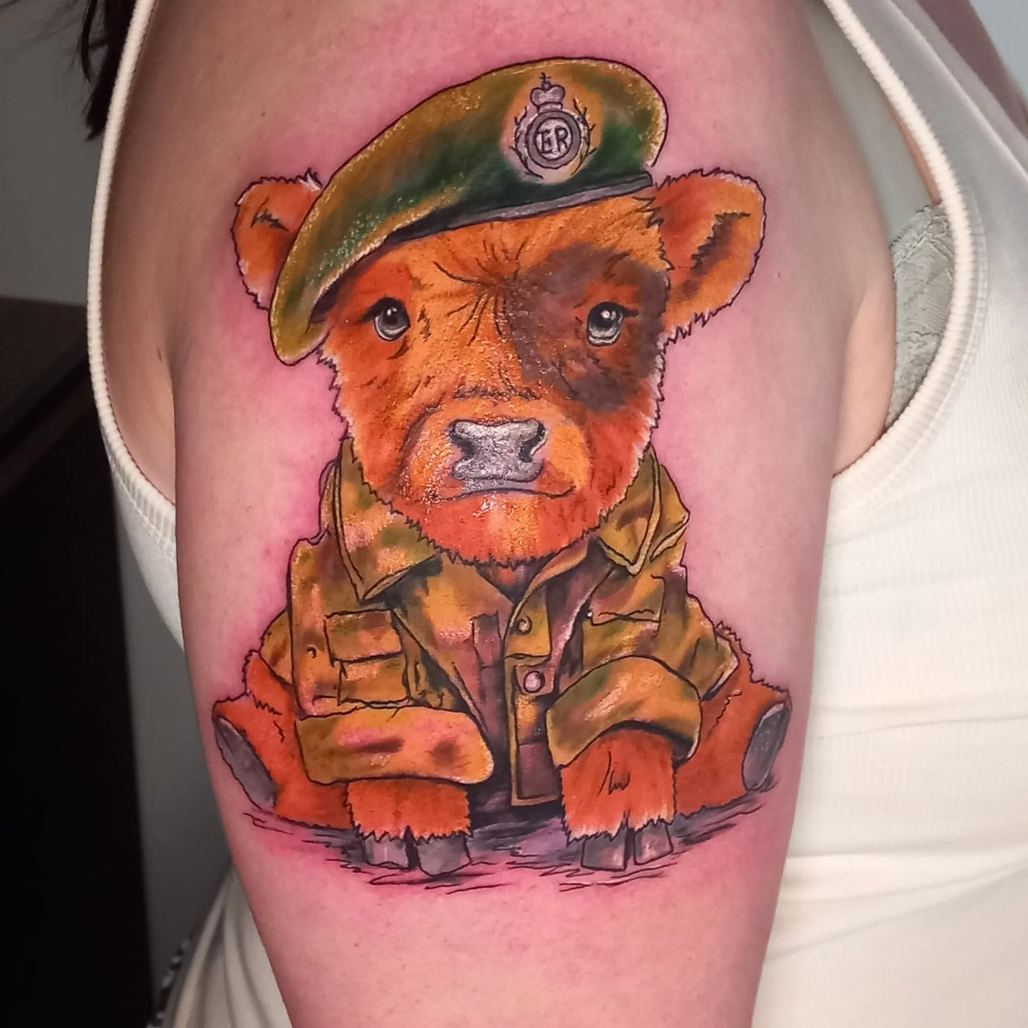Colorful tattoo of a bear's face wearing a military helmet with a badge on the helmet and the bears eyes are very expressive.