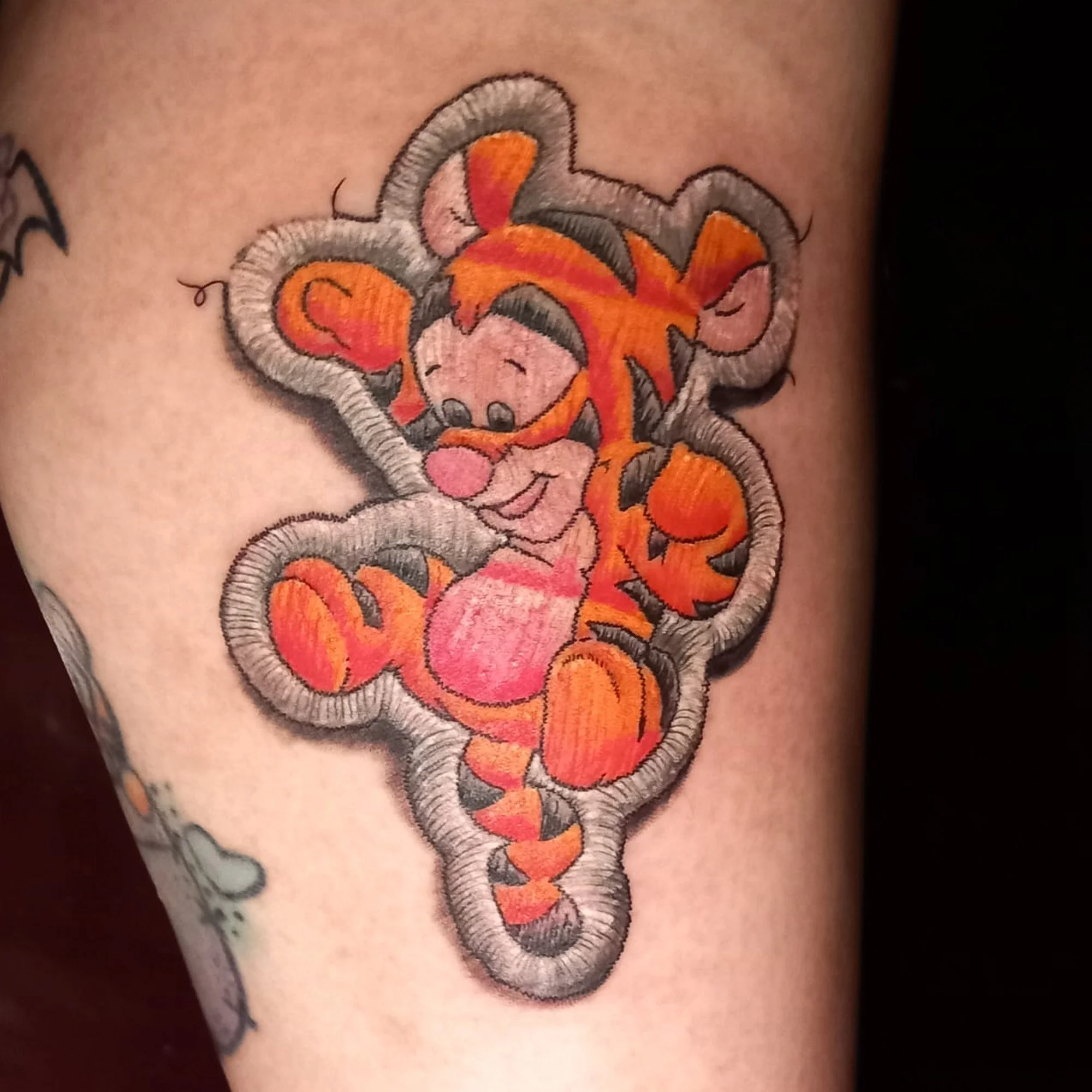 Colorful embroidered tiger face tattoo on skin.