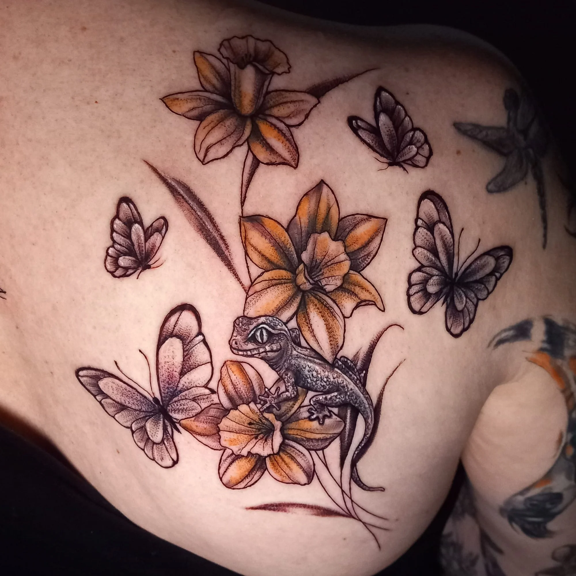 Tattoo of colorful flowers and butterflies on skin.