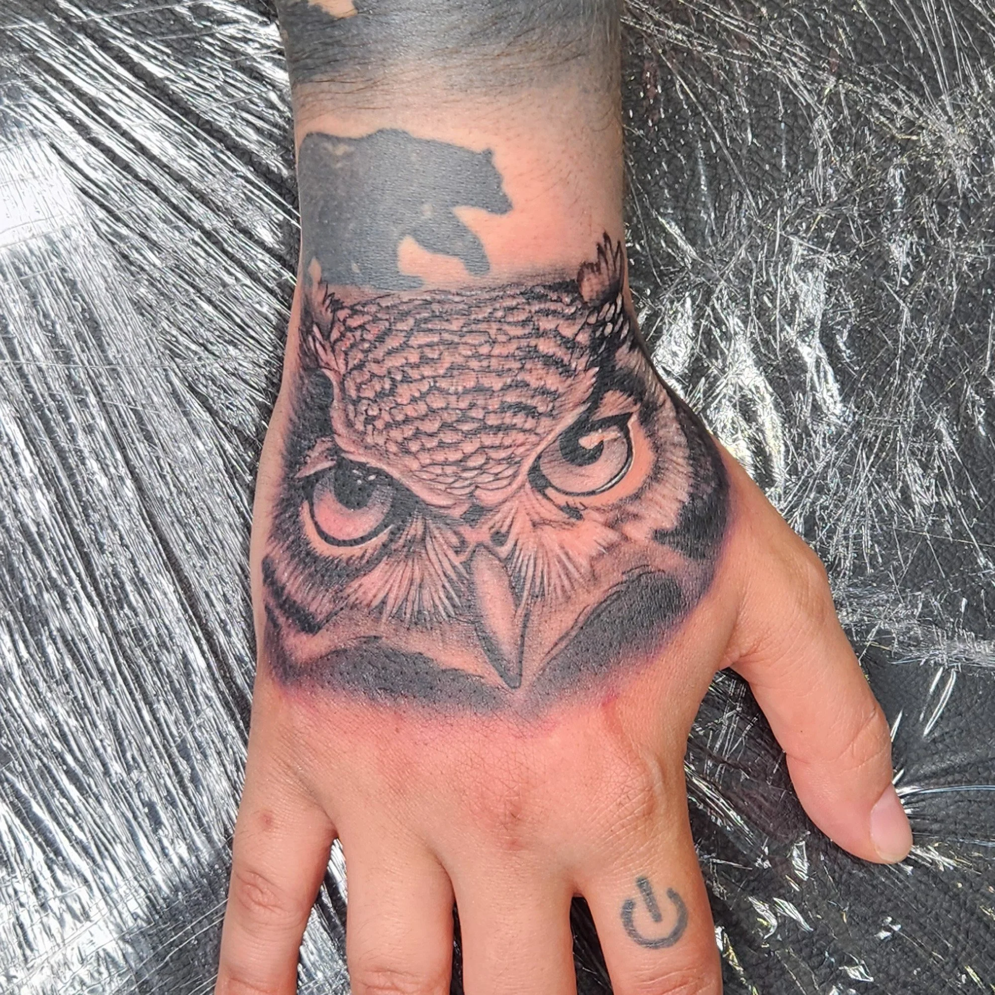 Realistic black and grey owl on hand tattoo