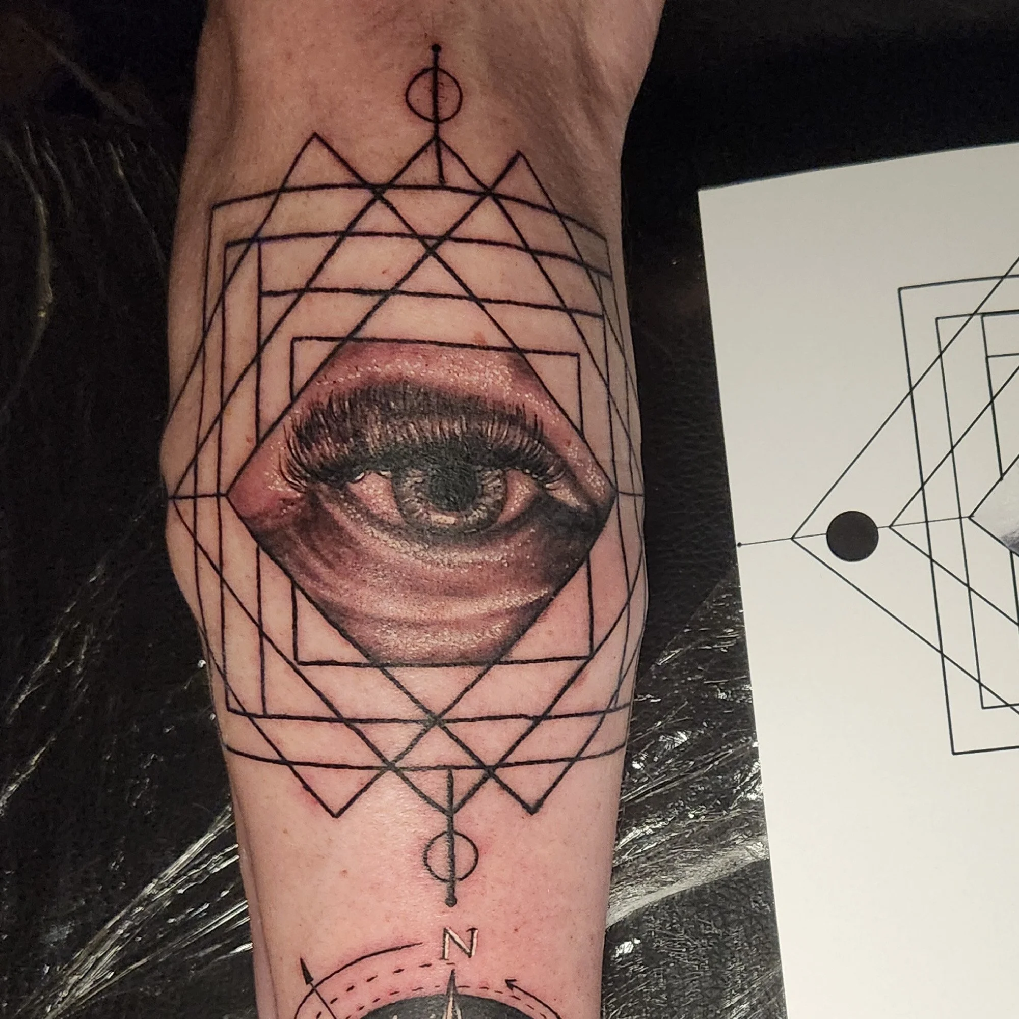 Black and grey realistic eye in geometric line work tattoo