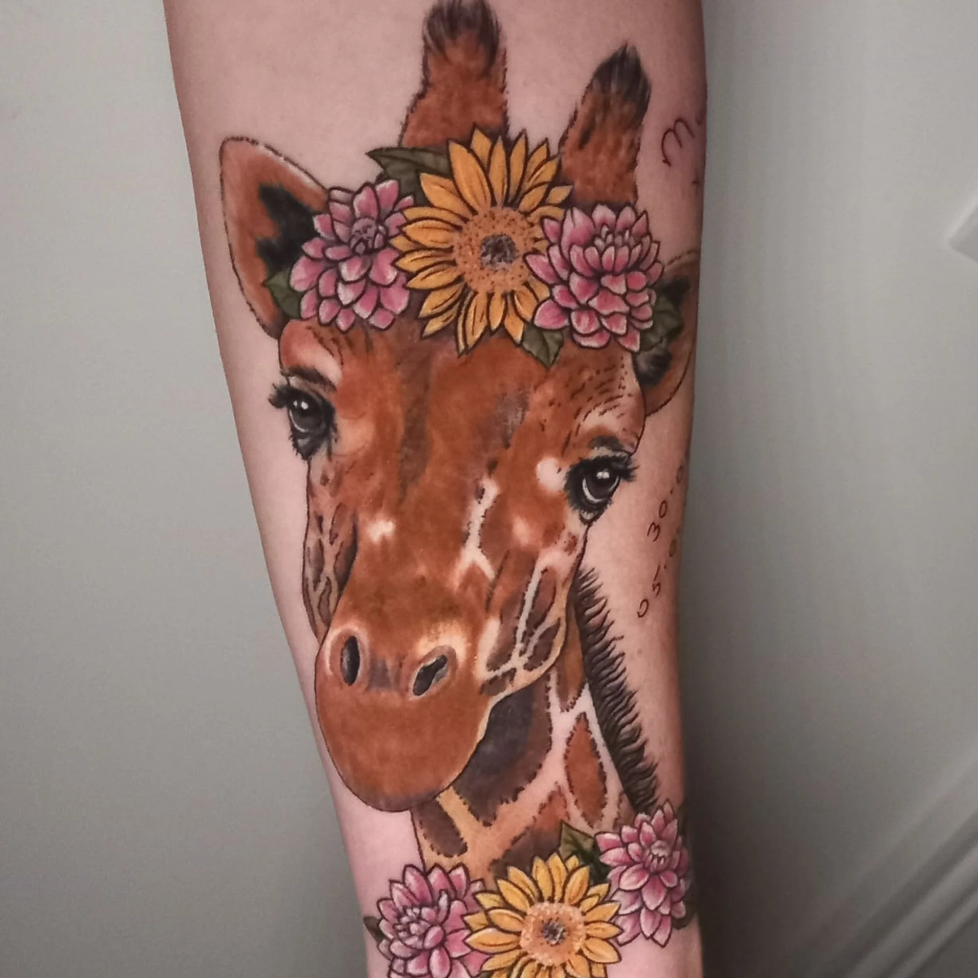 Tattoo of a Giraffe with flowers on it's head and around it's neck