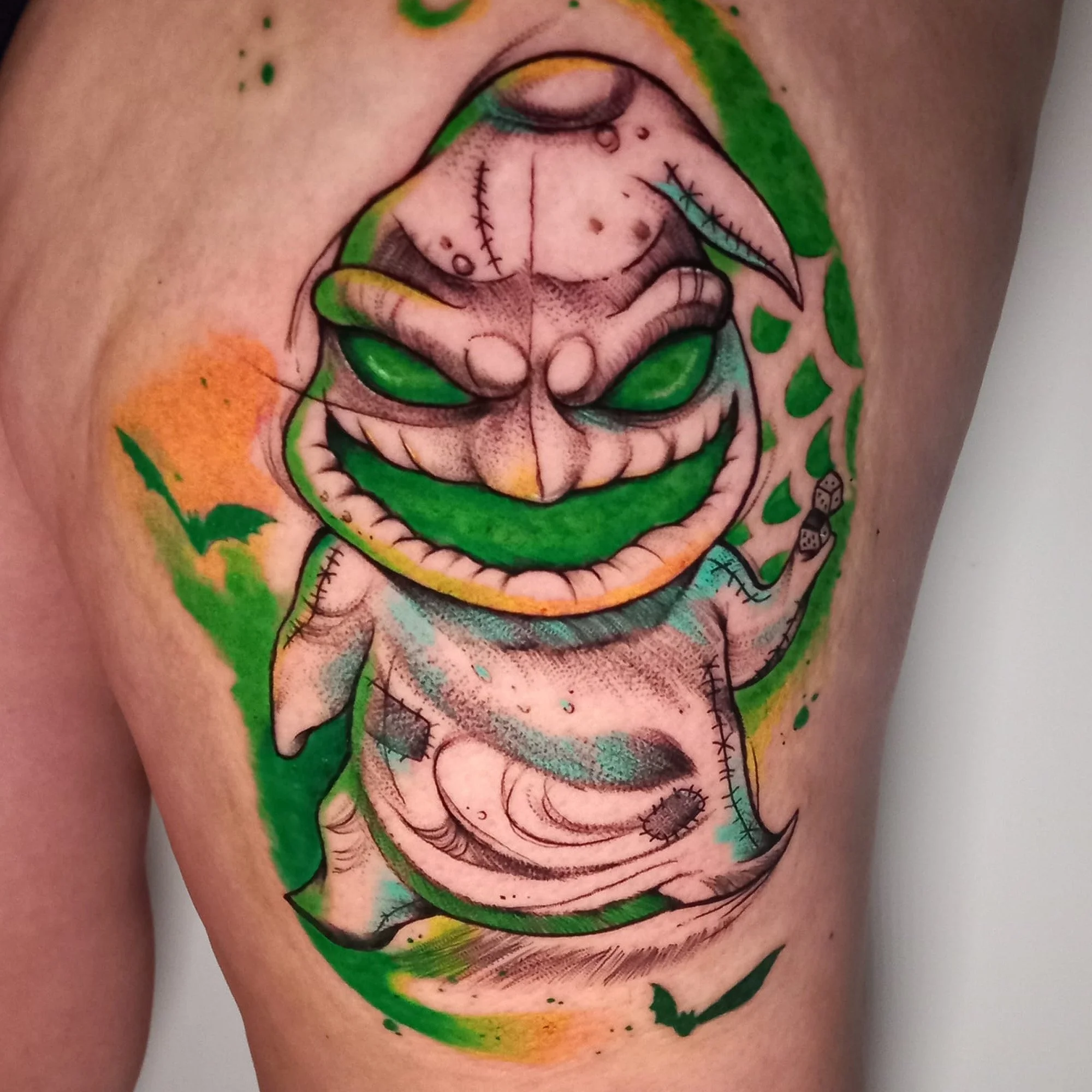 Colorful tattoo featuring a stylized face with closed eyes and various decorative elements.