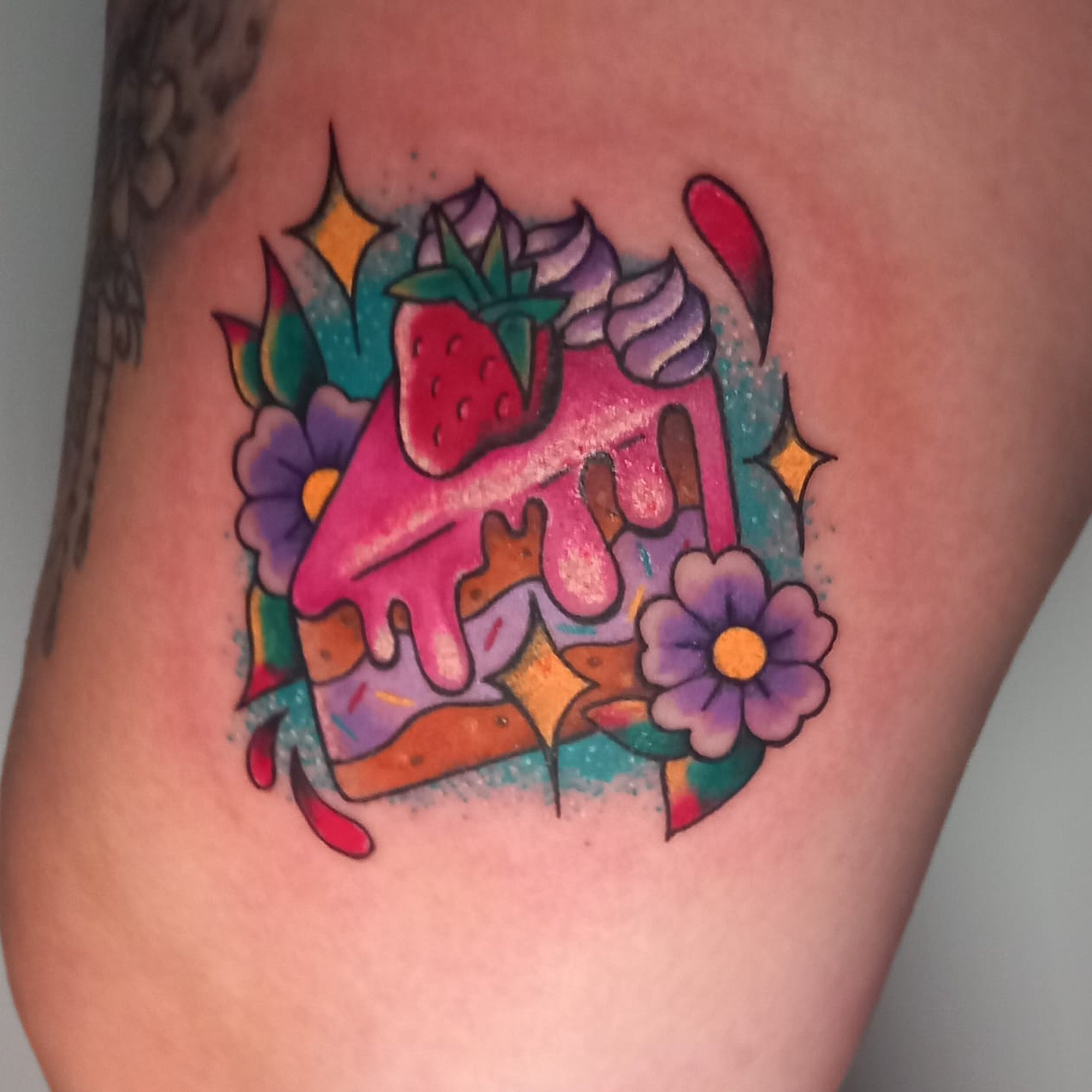 Colorful tattoo of strawberries, purple flowers, and stars on person's skin.
